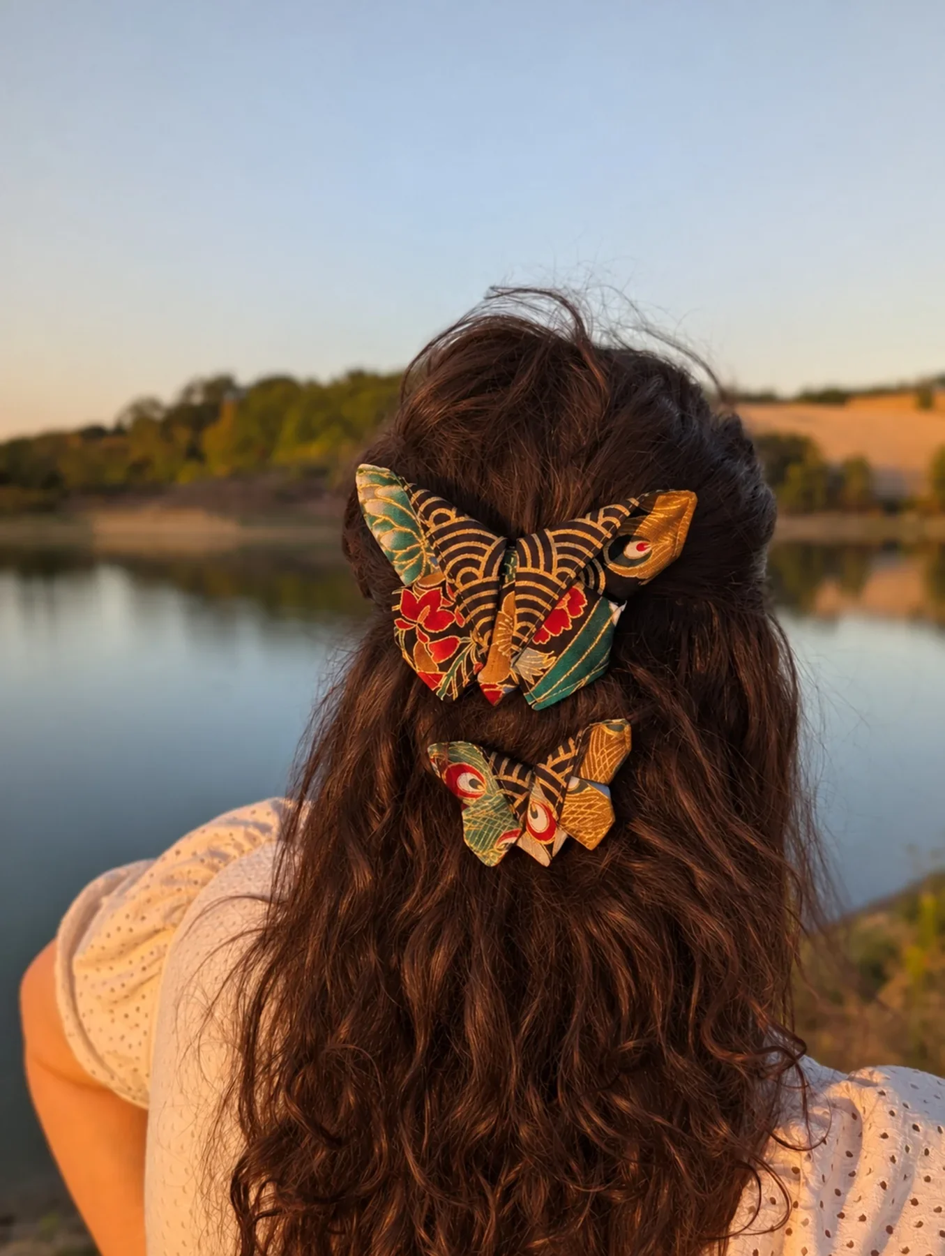 Grand et petit papillons origami multicolores portés ensemble sur cheveux colorés.