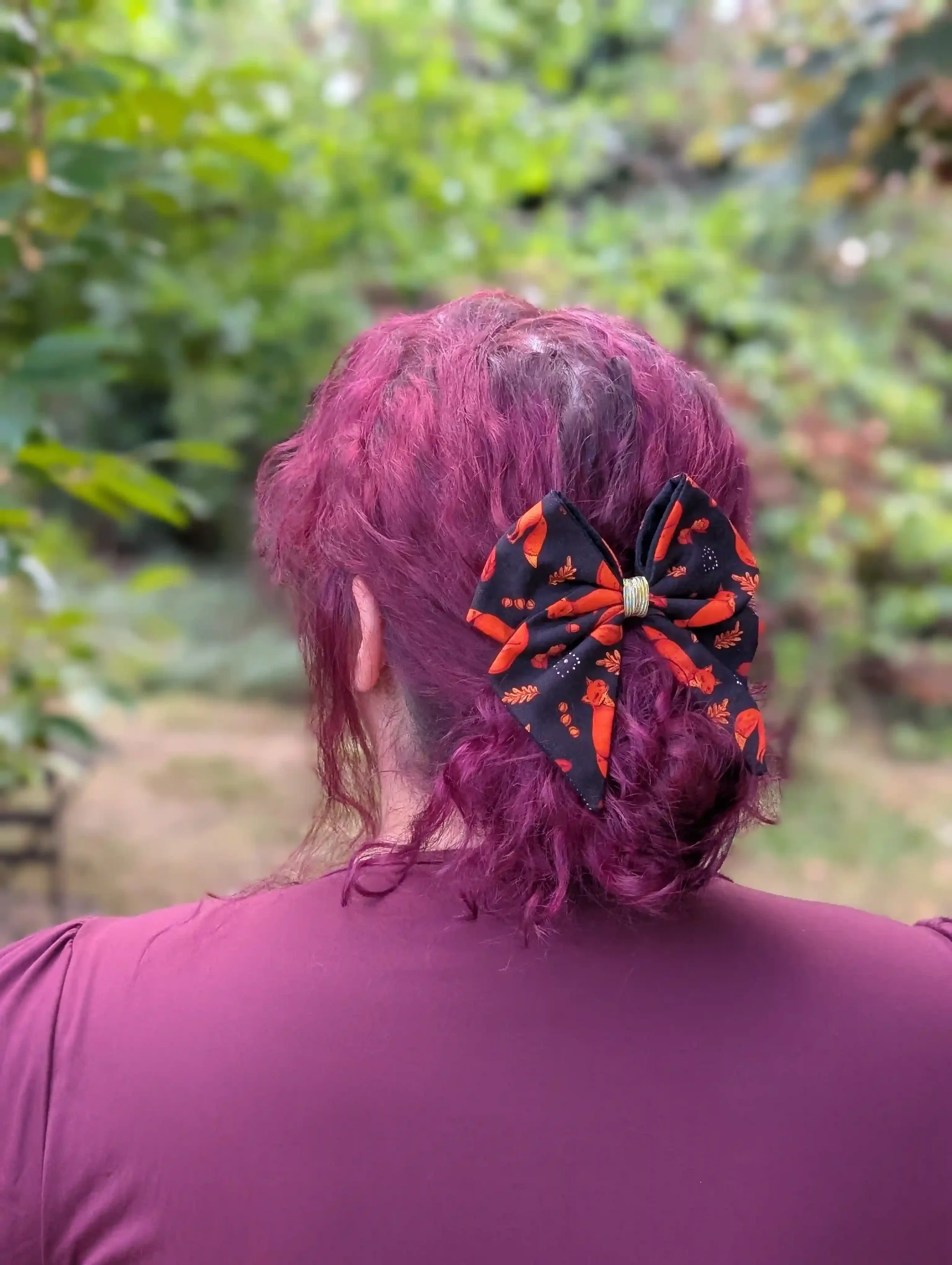 Nœud cheveux Renards porté sur un chignon bas, vue de dos, motif de petits renards roux sur fond noir.