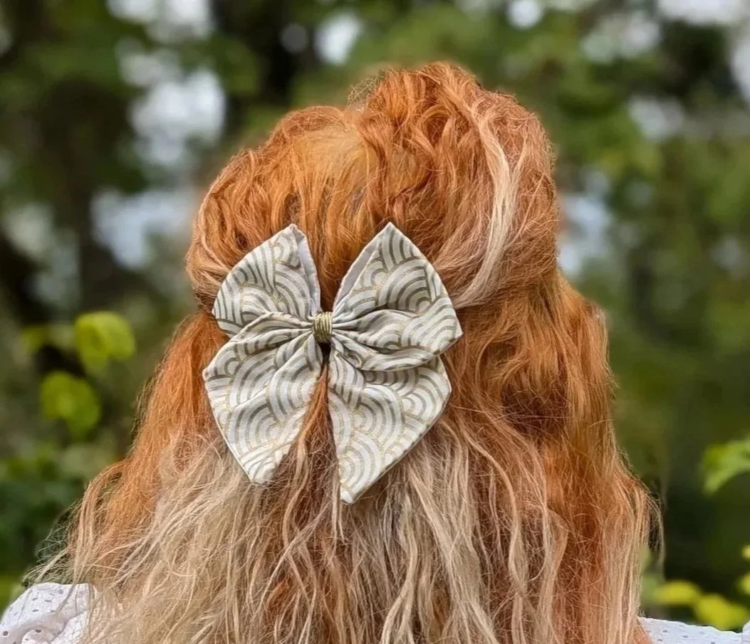 Nœud pour cheveux blanc aux motifs Seigaiha dorés, porté en demi-queue sur des cheveux roux, vu de dos