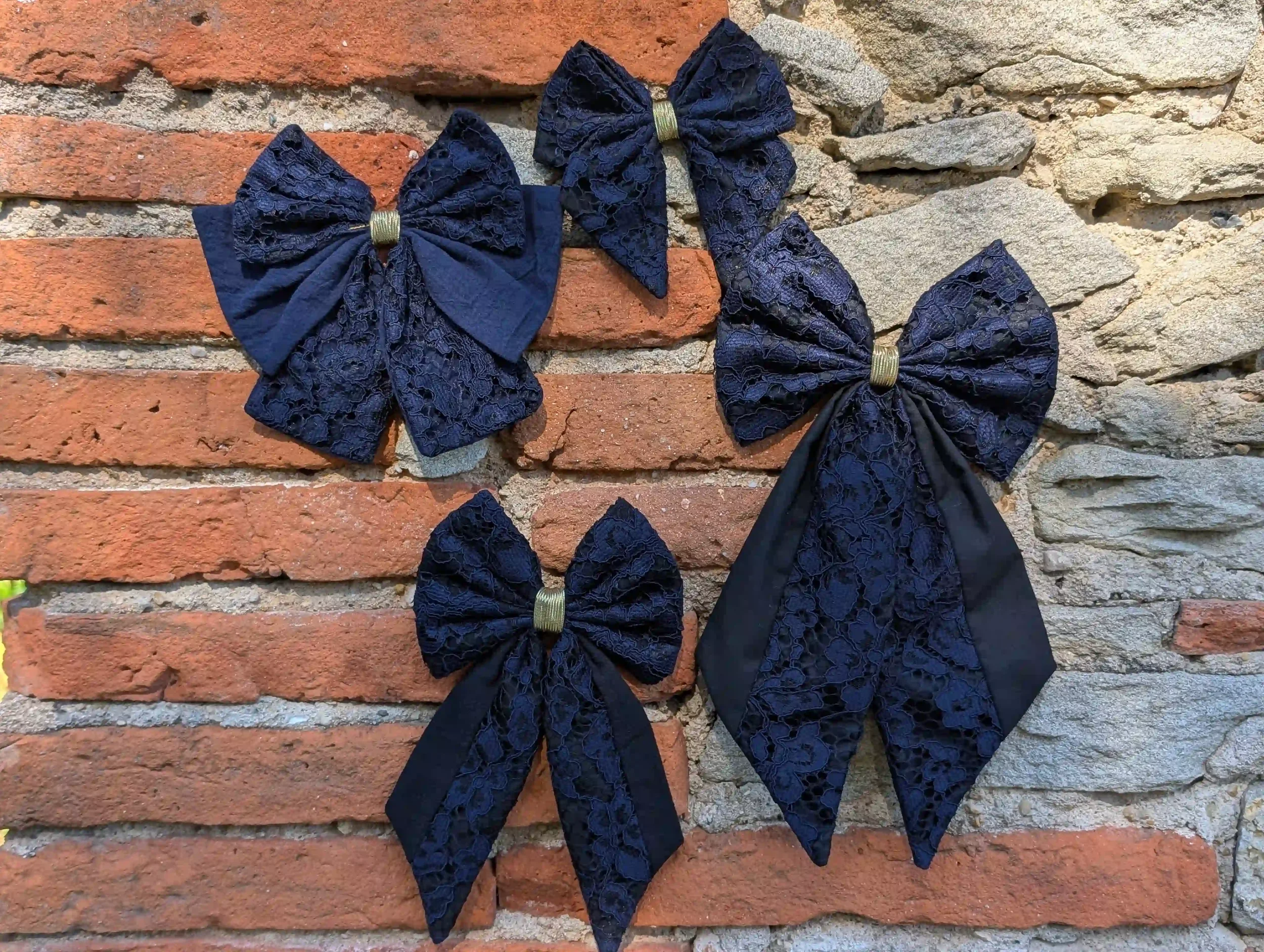 Collection de nœuds pour cheveux en dentelle bleu nuit et tissu noir, présentés en plusieurs tailles.