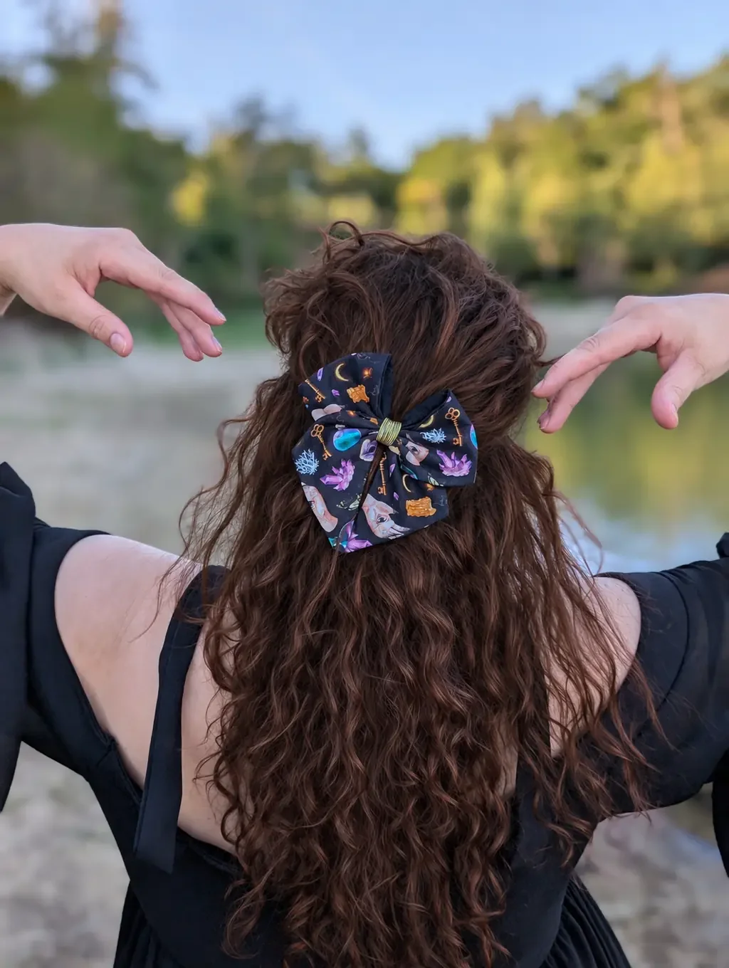 Nœud barrette Clés d’Arcane à mains mystiques et cristaux porté en demi-queue sur cheveux bruns.