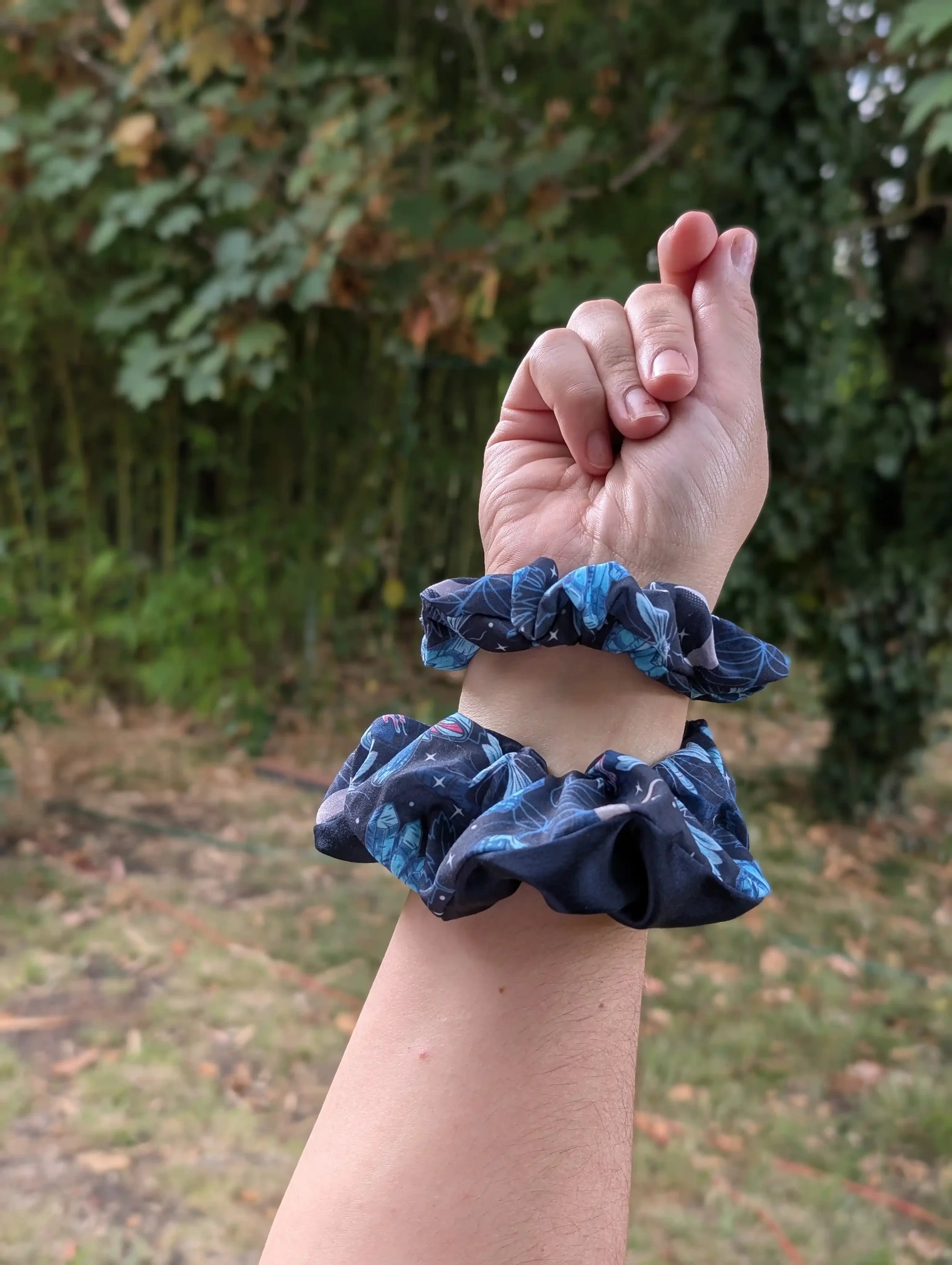 Deux chouchous Cristal noir et bleu de tailles différentes portés au poignet, comme des chouchous bracelets.
