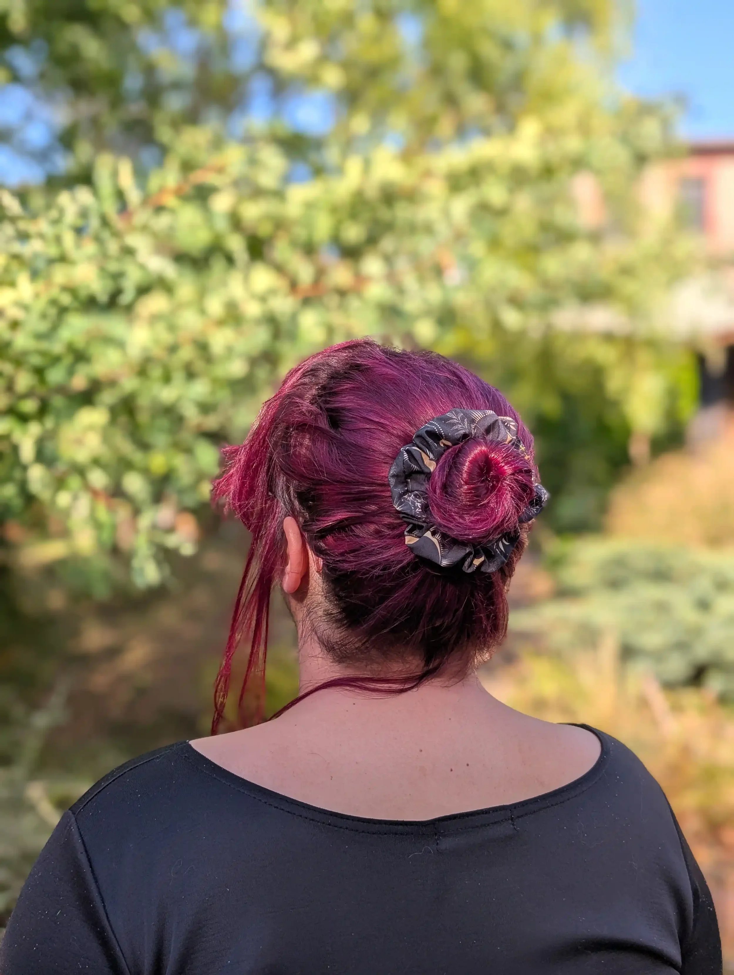 Petit chouchou Dark Moon vu de dos sur un chignon, motifs célestes noirs et dorés
