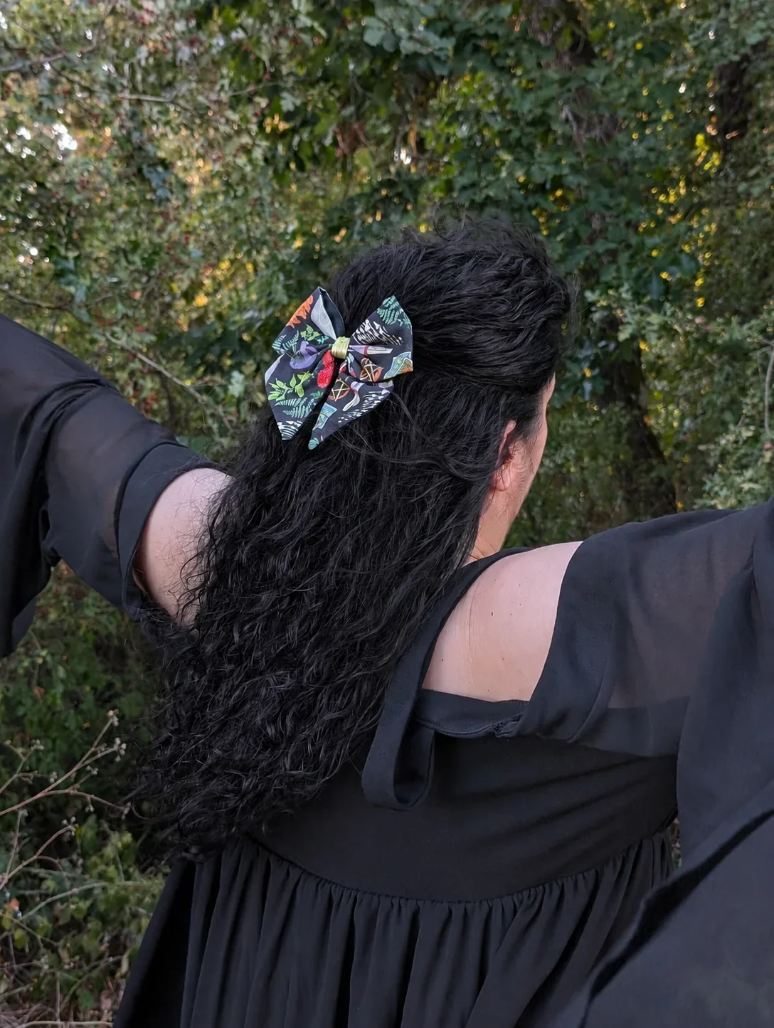Noeud Grimoire des bois dans une demi-queue de cheveux noirs, photographié de côté dans les bois.