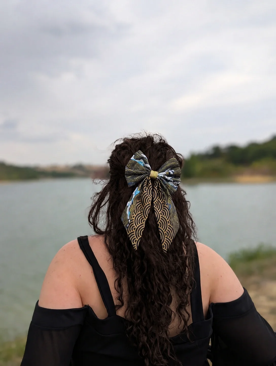 Nœud pour cheveux Nami to Awa à motifs japonais bleus et dorés porté sur cheveux longs, vue de dos.