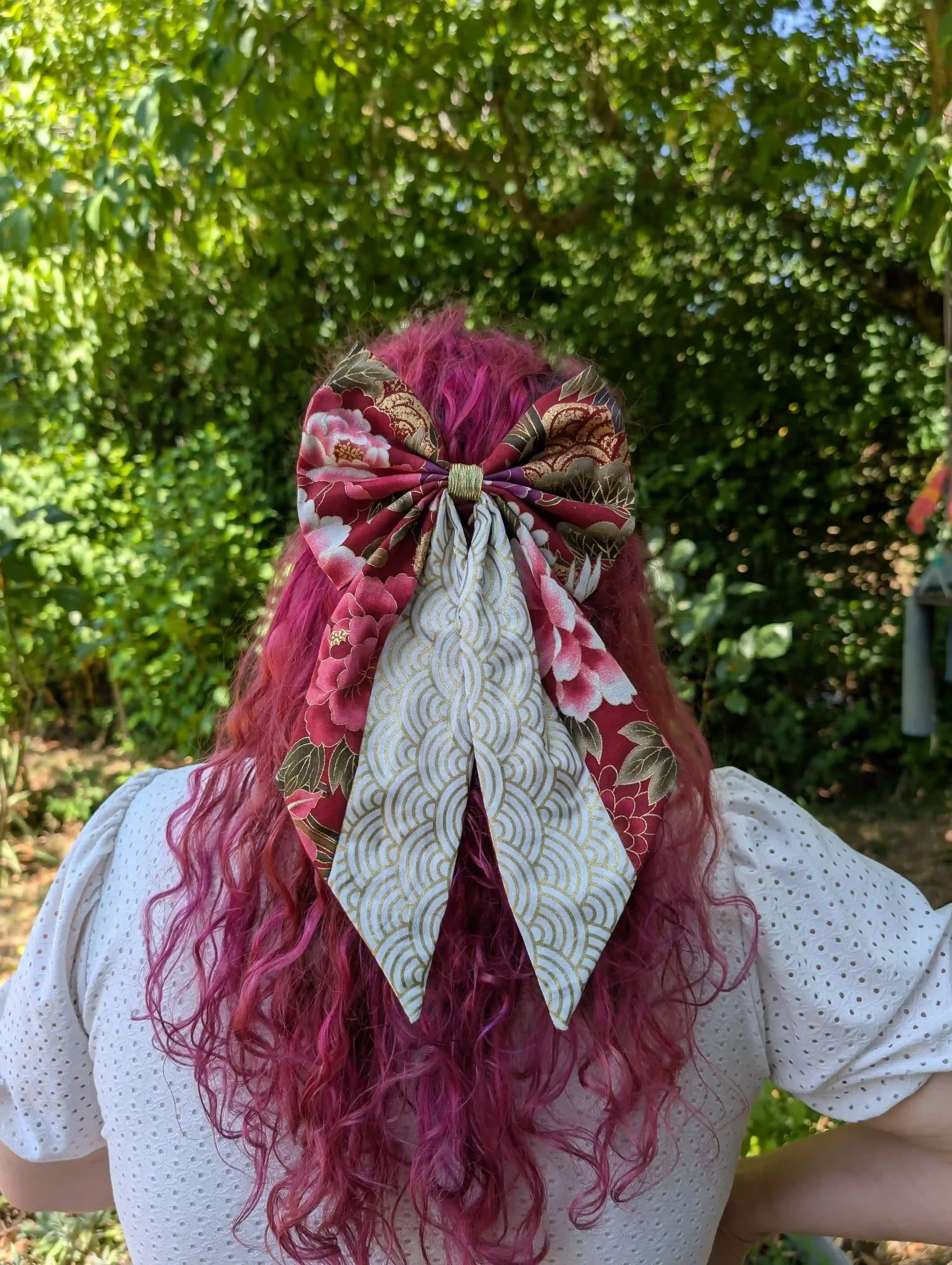Grand nœud cheveux Tsuru rouge et or porté sur une demi-queue de cheval, vue de face, en tissu japonais.