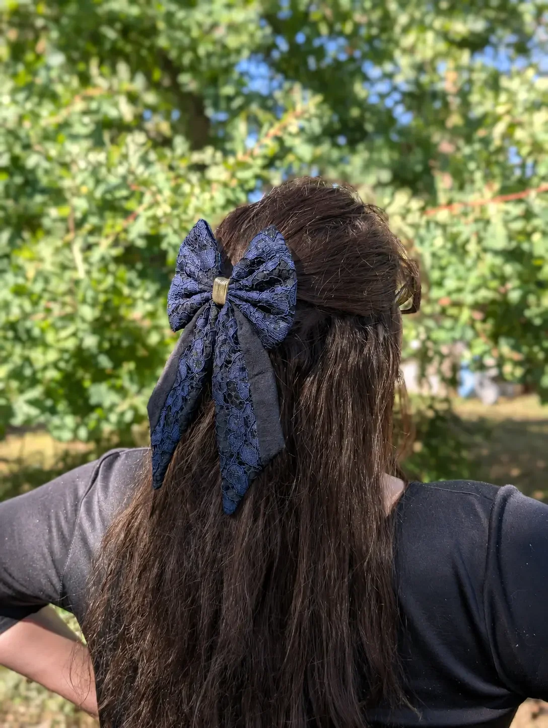 Grand noeud barrette en dentelle bleu nuit et noir porté sur une demi-queue de cheveux.