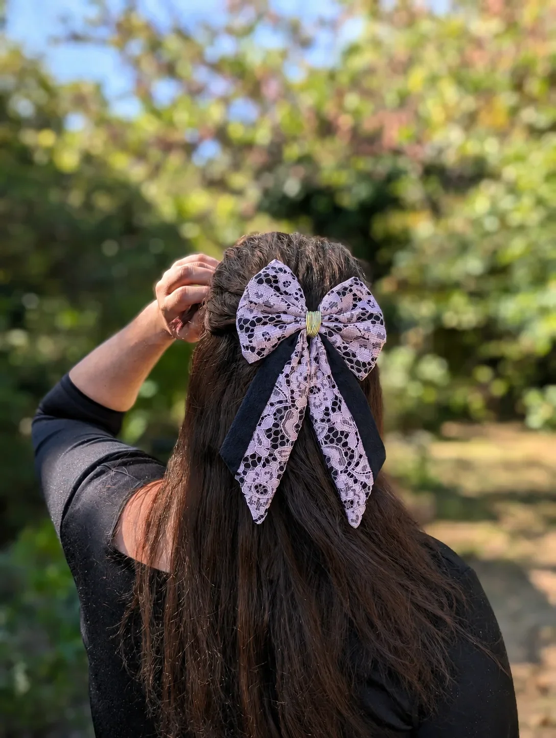 Grand noeud pour cheveux en dentelle rose lilas et tissu noir, porté sur une demi-queue.