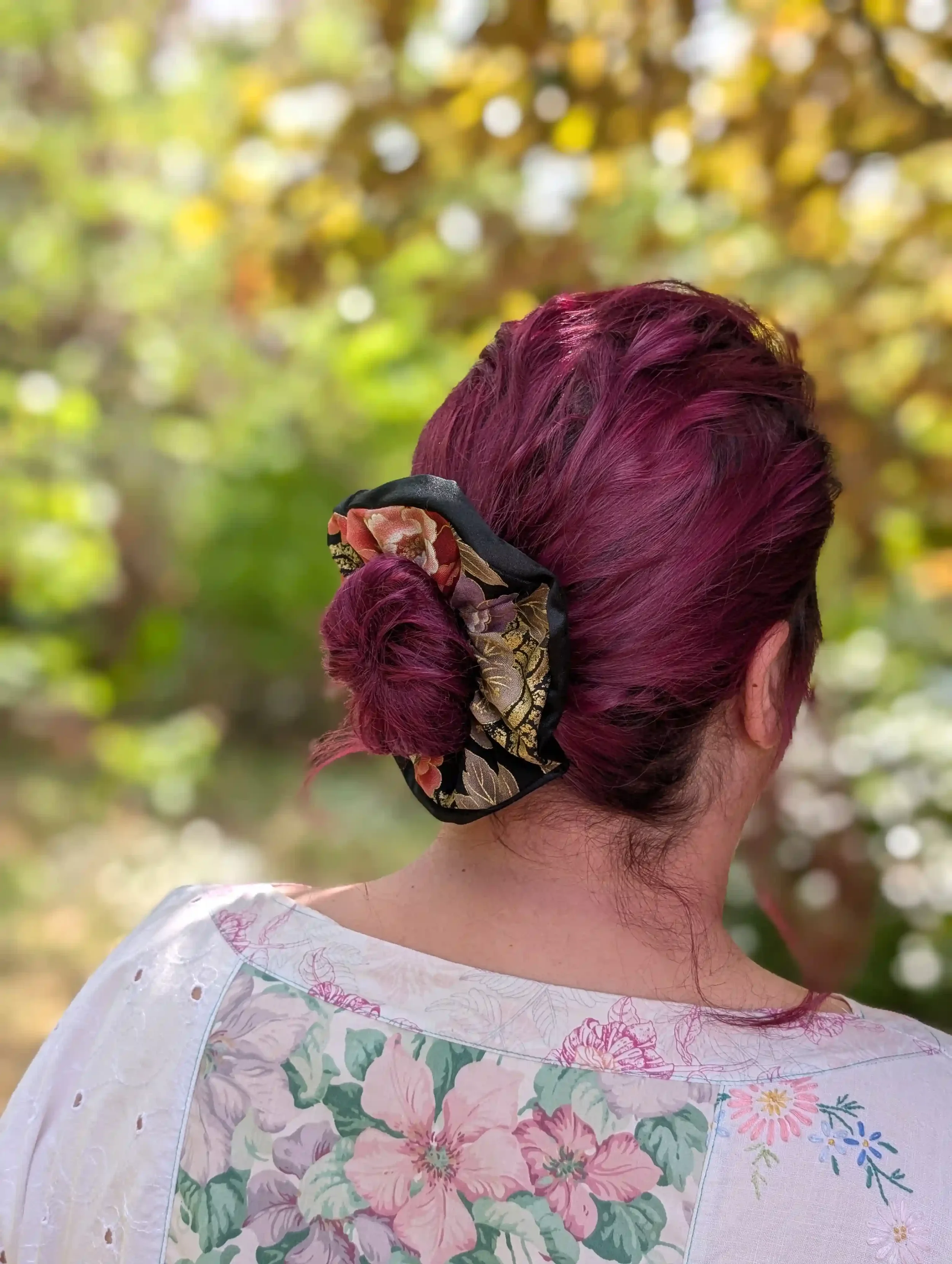 Grand chouchou cheveux Tsuru noir et or porté sur un chignon, motif floral japonais doré et satin noir.