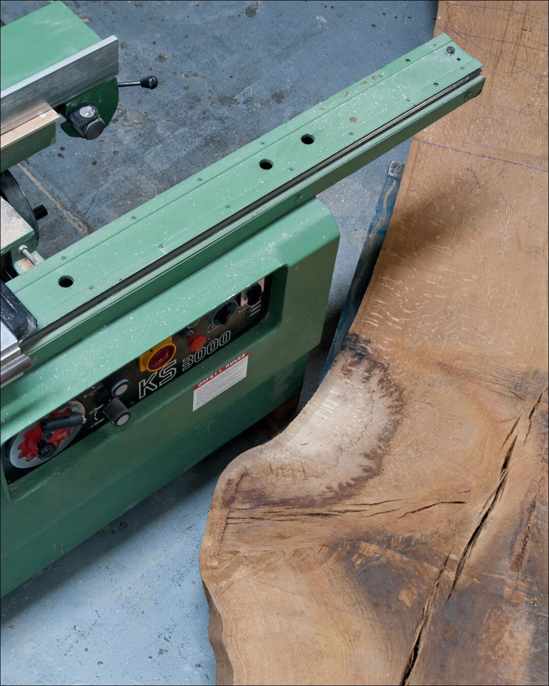 Casadei Table saw machine next to a large piece of natural wood in By Daves workshop.