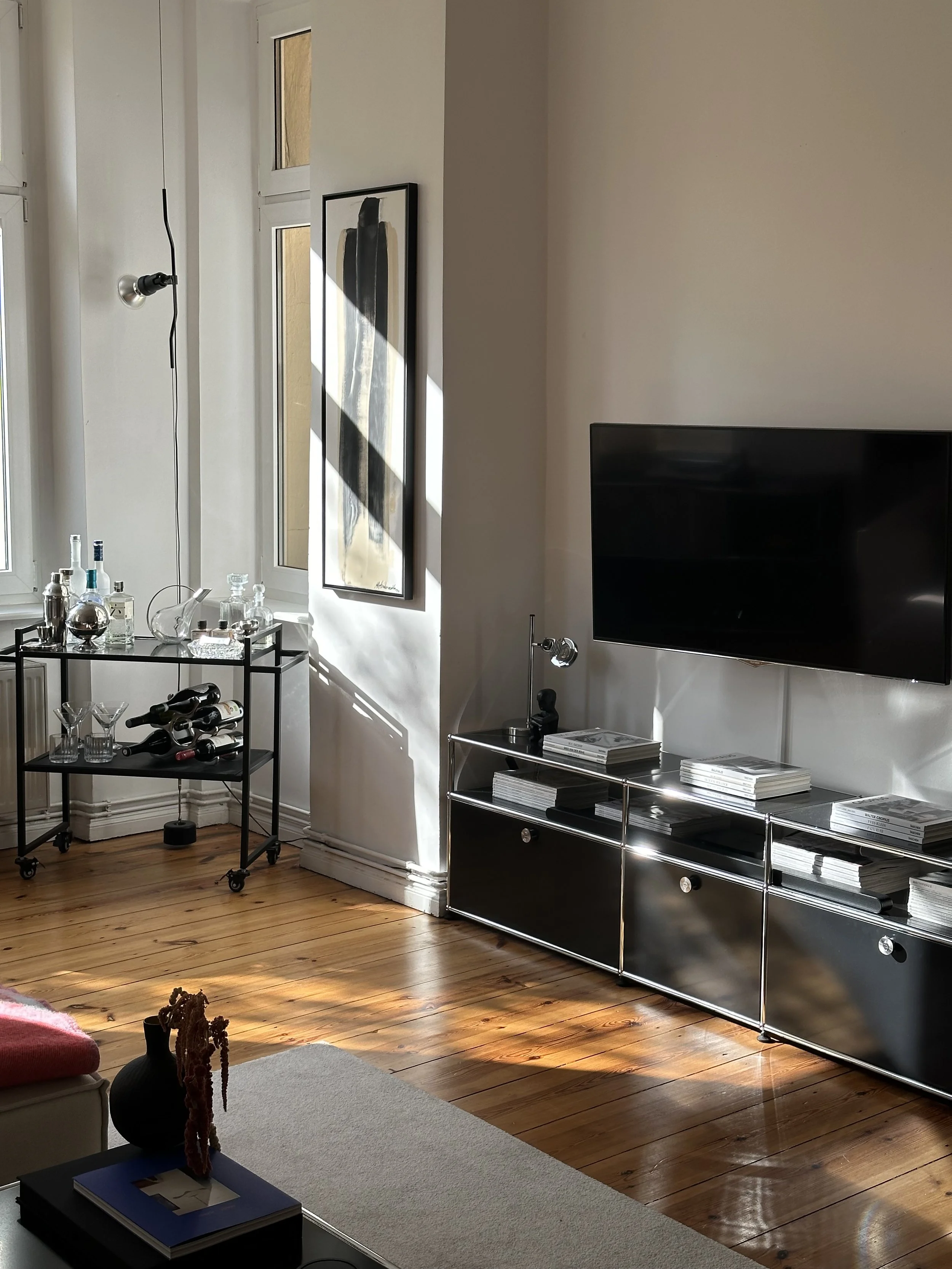 Wohnzimmer mit einem schwarzen USM TV Board, im Hintergrund ein Barwagen