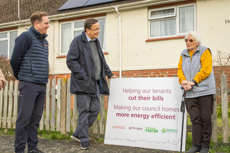 UPOWA and Winchester City Council with tenant outside council home upgraded with solar panels as part of retrofit programme