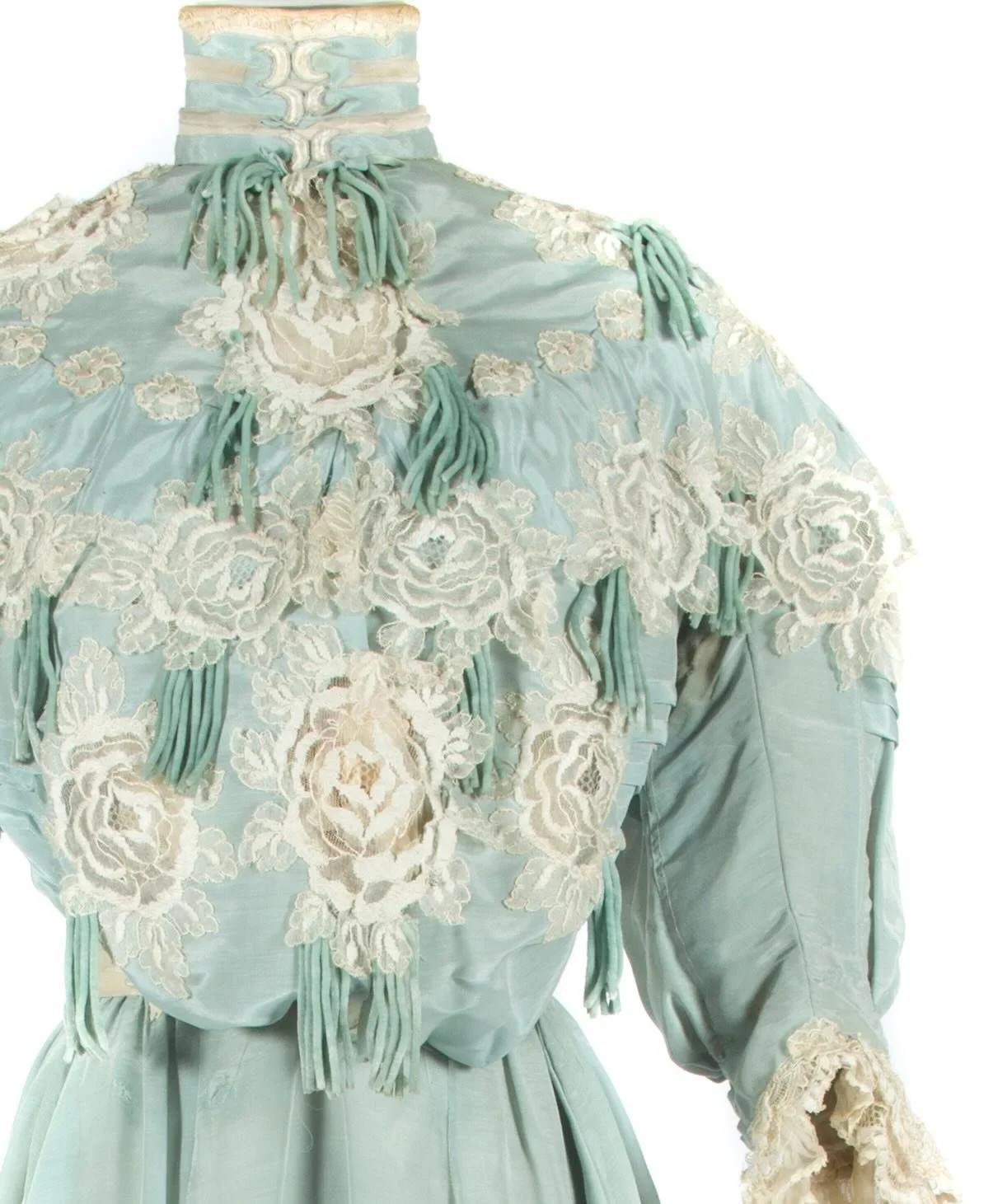 🩵 &ldquo;This two piece evening dress is made of blue silk and has a standing collar. There is heavy blousing at the front of the boned bodice that is decorated with rose appliques. The large sleeves have lace trim around the cuffs and there is a si