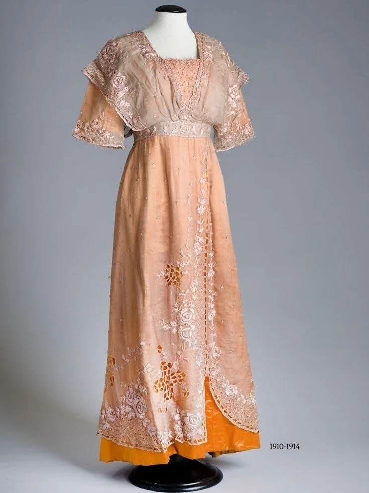 🍊 &ldquo;A dress of orange silk satin with an overdress of mushroom coloured chiffon (pink shot with green). A loose fitting bodice with squared neckline and raglan sleeves with a slim straight ankle-length skirt. The over bodice has a shawl collar,
