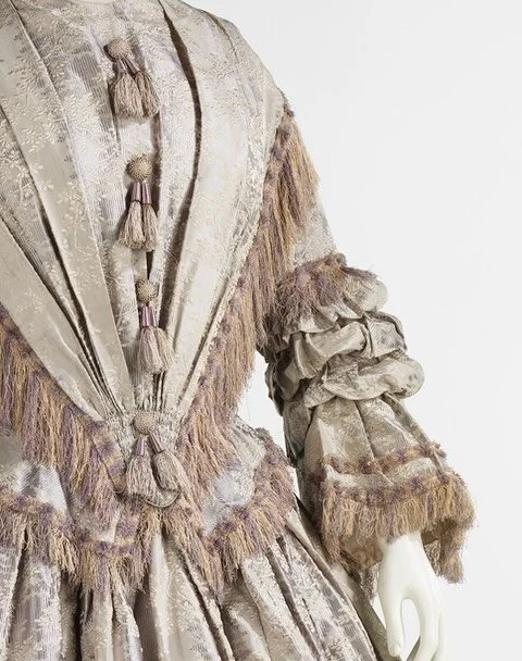🩶 &ldquo;Fashionable dress of the 1840s was inspired by Queen Victoria (1819-1901) who was crowned in 1838. Due to her modesty and youth she favored styles which were reserved as befitted a young queen. The elongated bodice and wide V-shape over the