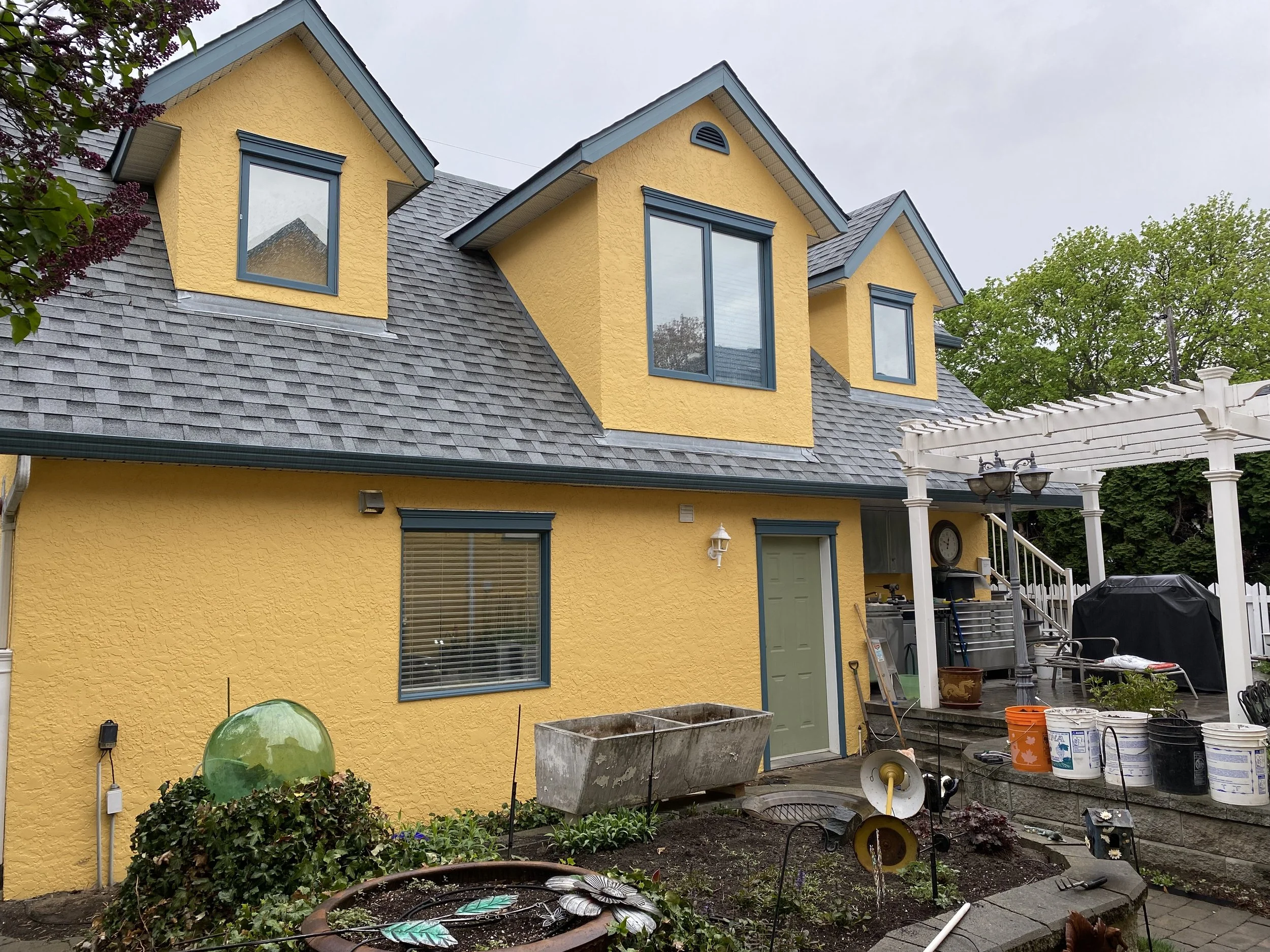 Exterior house painting in Vernon BC showing freshly painted yellow home with detailed prep work completed