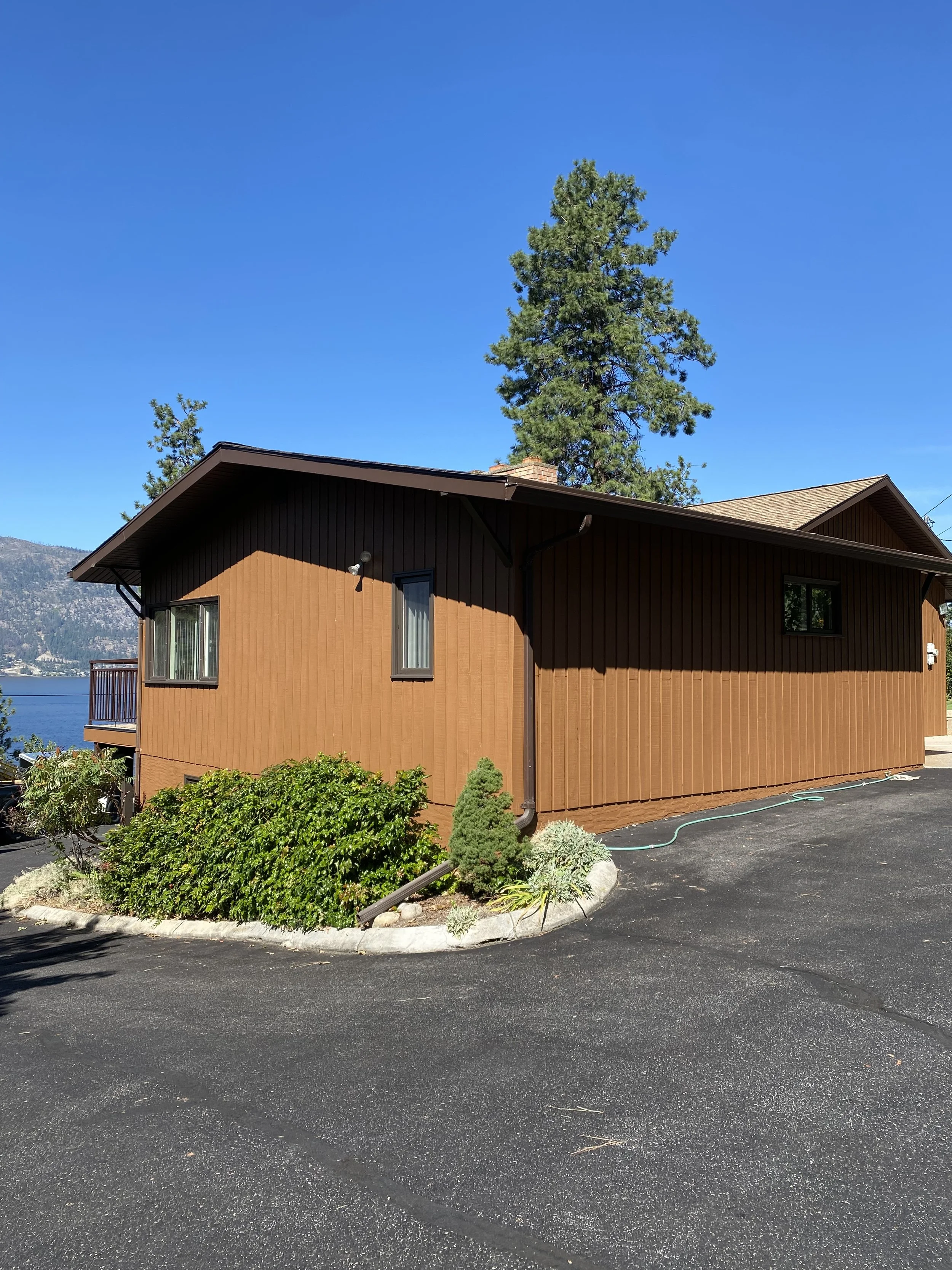 brown-board-and-batten-exterior-stain-on-okanagan-landing-home-with-lake-view