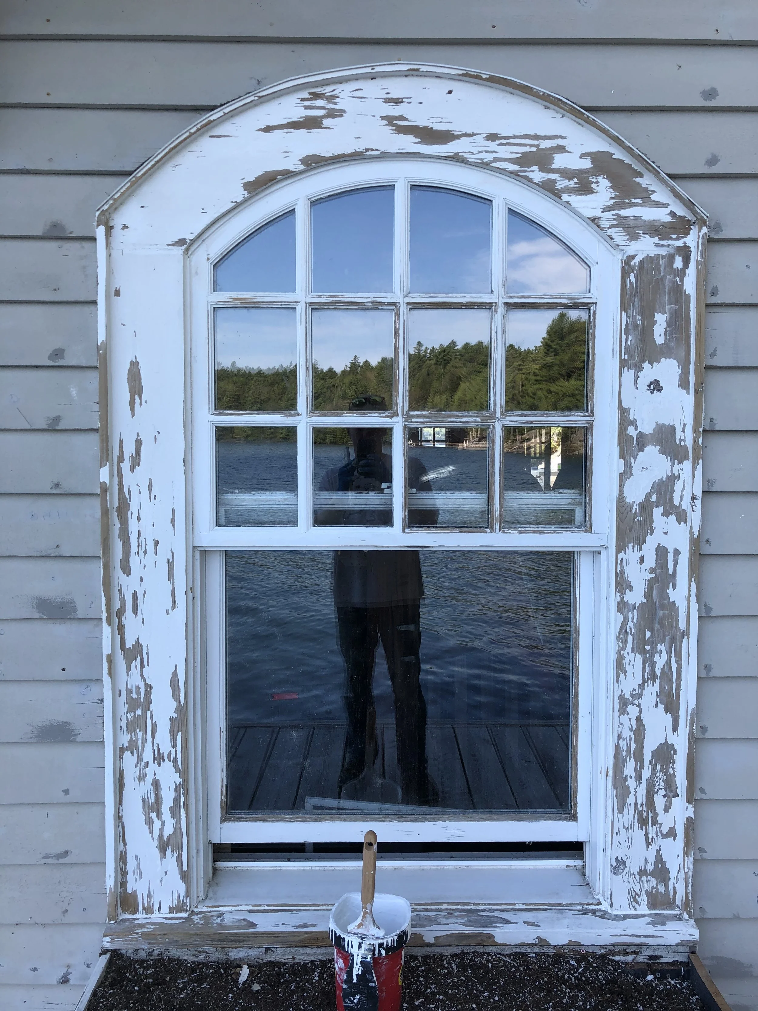 Exterior house painting in Vernon BC with painter using lift for second storey siding work