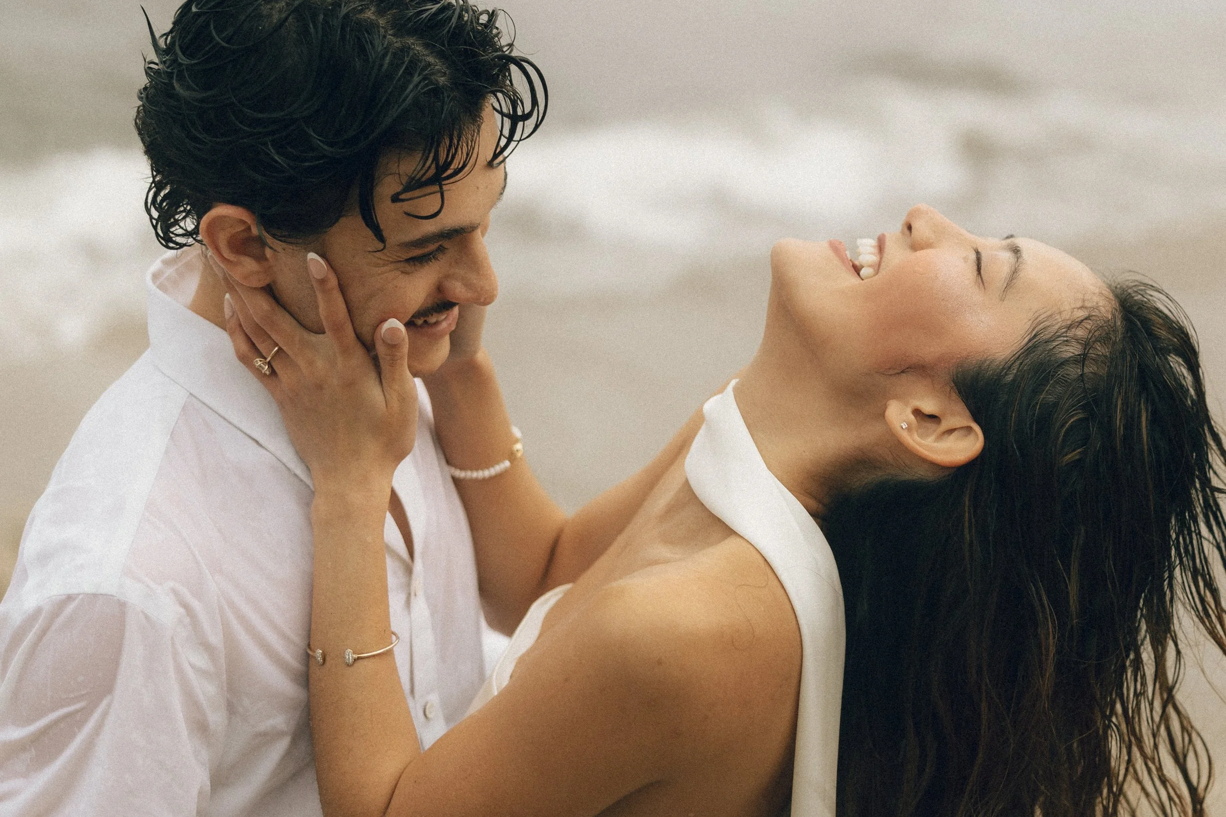 A man and a woman are smiling and looking at each other, with the man's face close to the woman's face. They appear to be happy and enjoying each other's company.