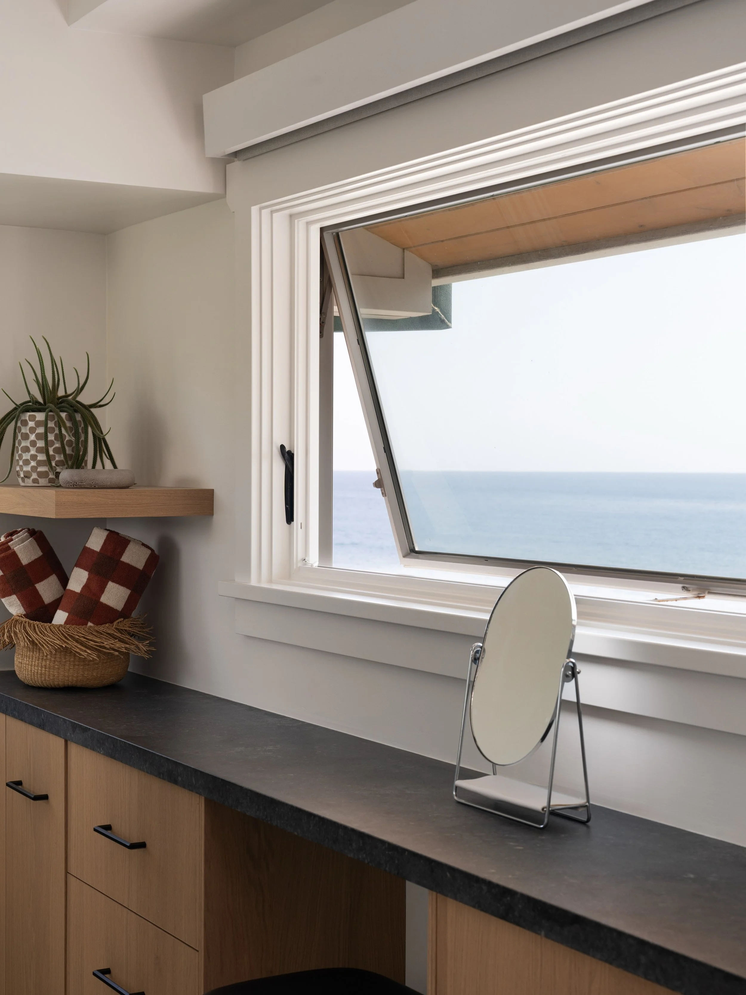 A little moment with a pretty incredible view. 🤍

We designed this built-in vanity in the primary bathroom to feel simple, warm, and intentional, white oak cabinetry, a dark stone countertop, and an awning window that lets in the ocean breeze withou