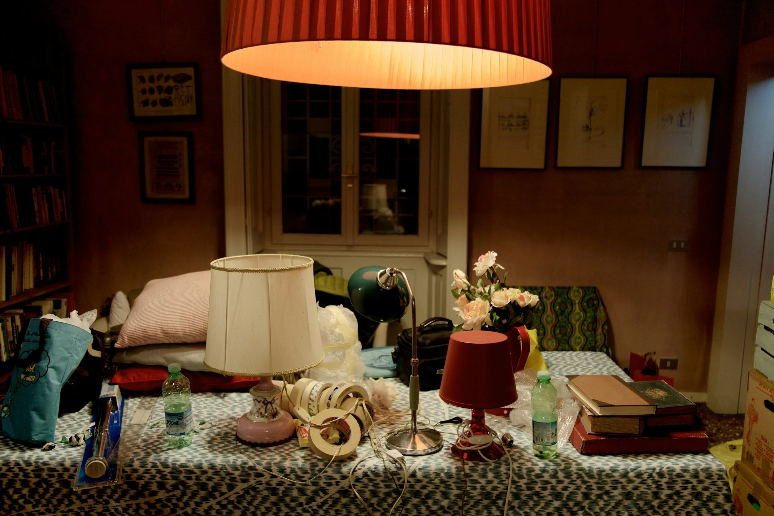A selection of vintage props, including lamps with shades, a stack of books, and roses on a black and white patterned tablecloth.