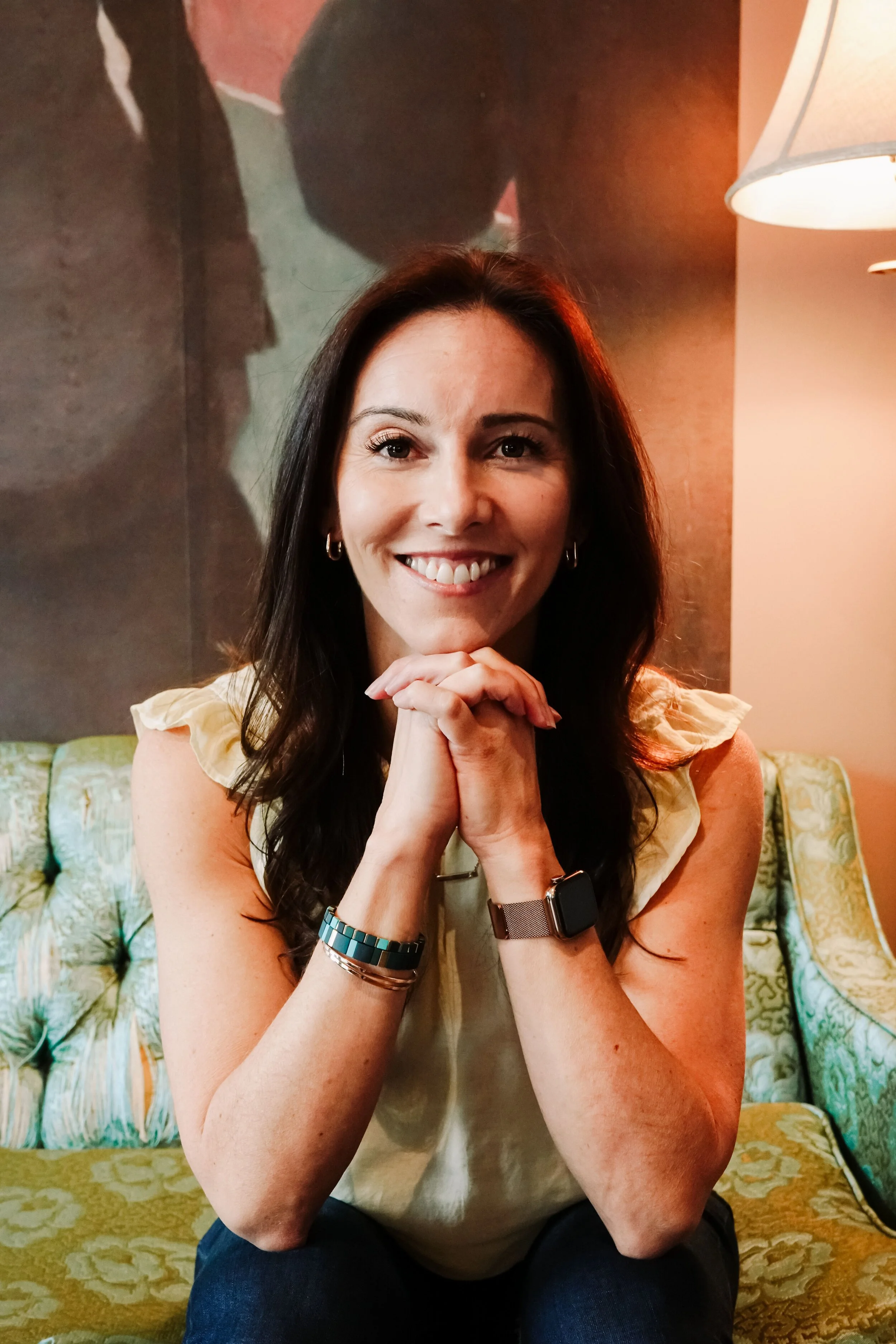 Amanda Hinman sitting on a couch and smiling in a headshot portrait