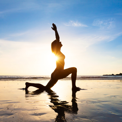 A woman practicing yoga on the beach.