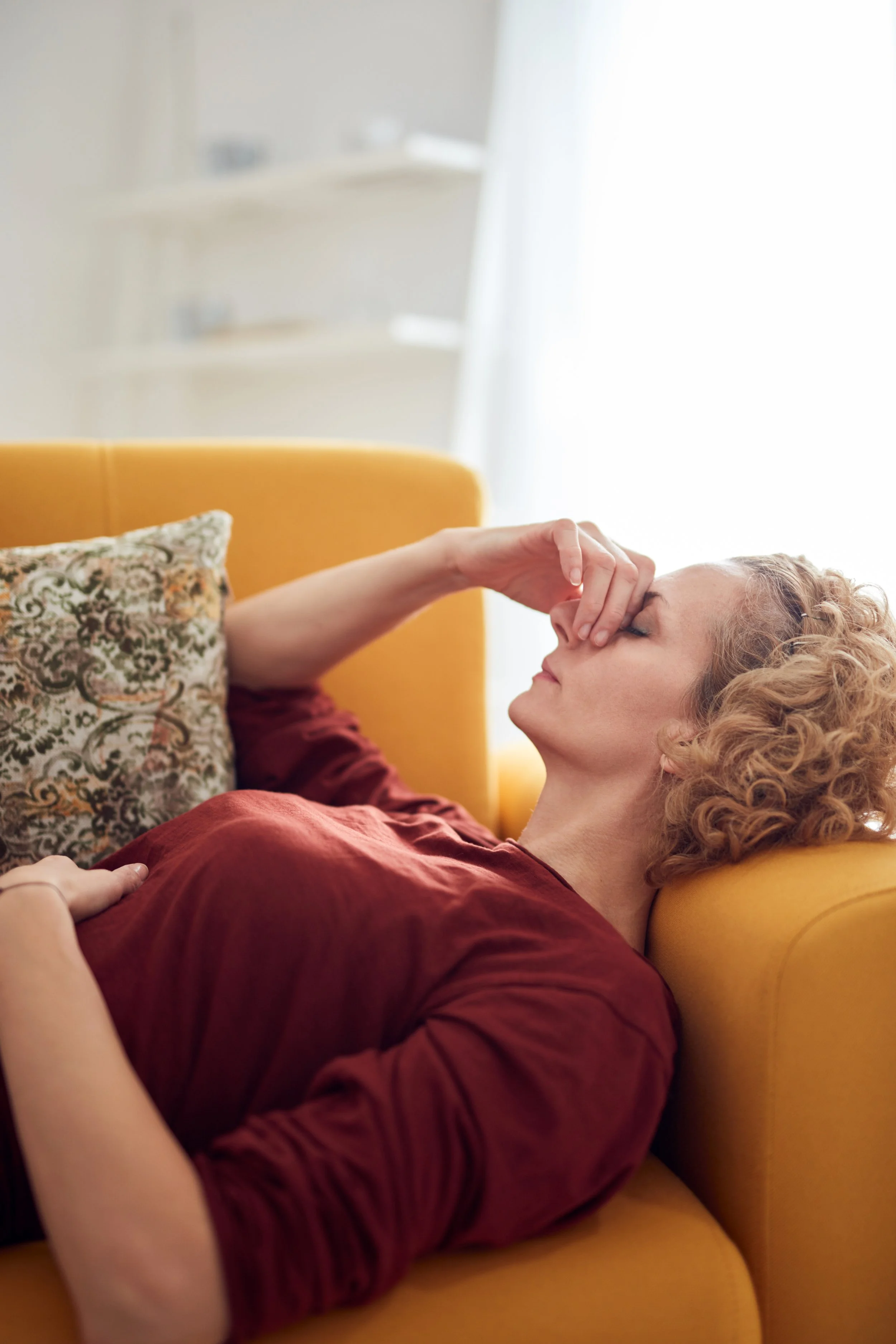 A woman lying on the couch, stressed, and touching her nose