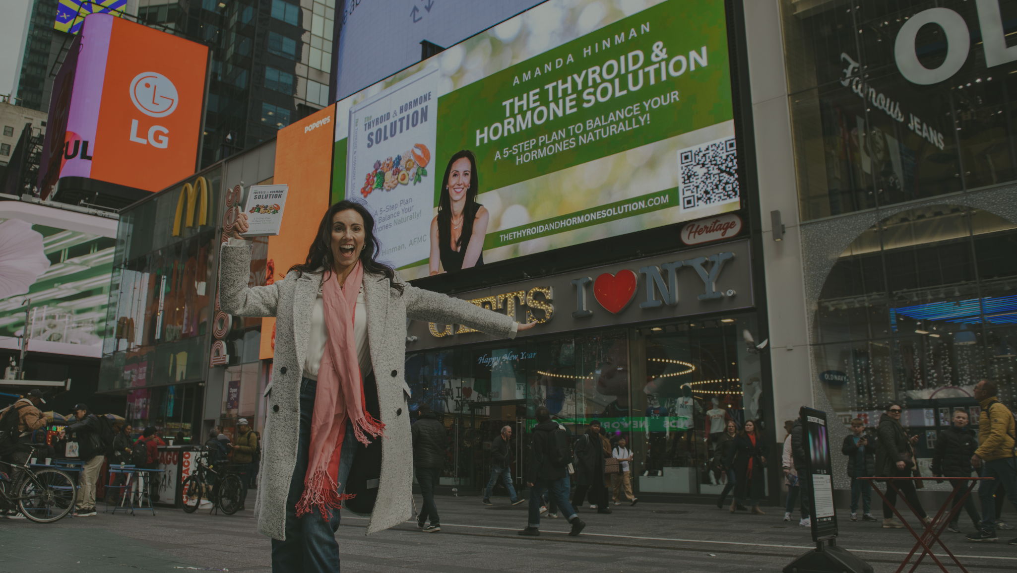 Amanda Hinman holding her book in New York Times Square.