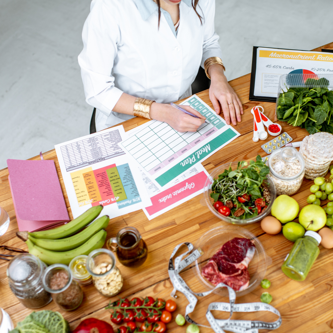 A woman writing in a meal planner at a table surrounded by healthy foods