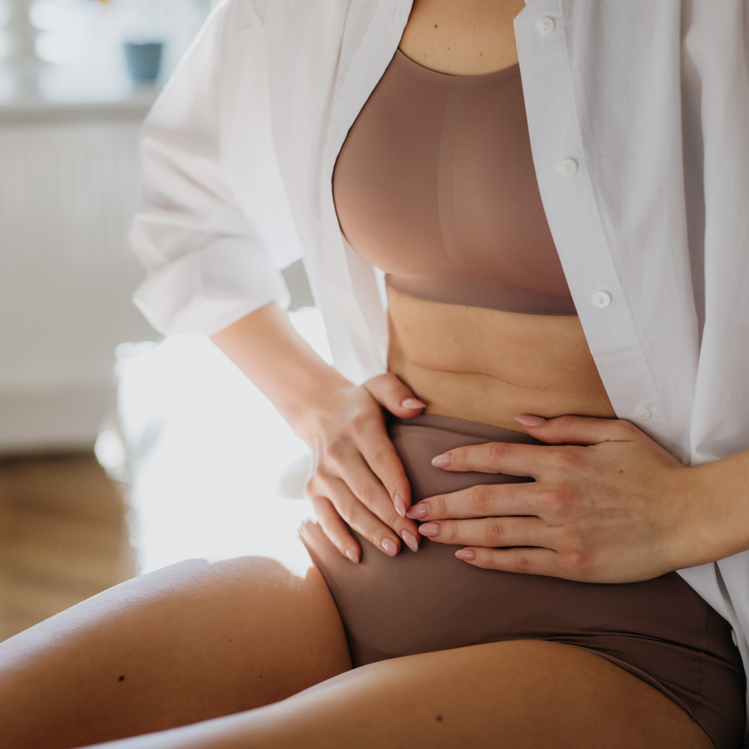 A woman holding her bloated stomach despite eating healthy food