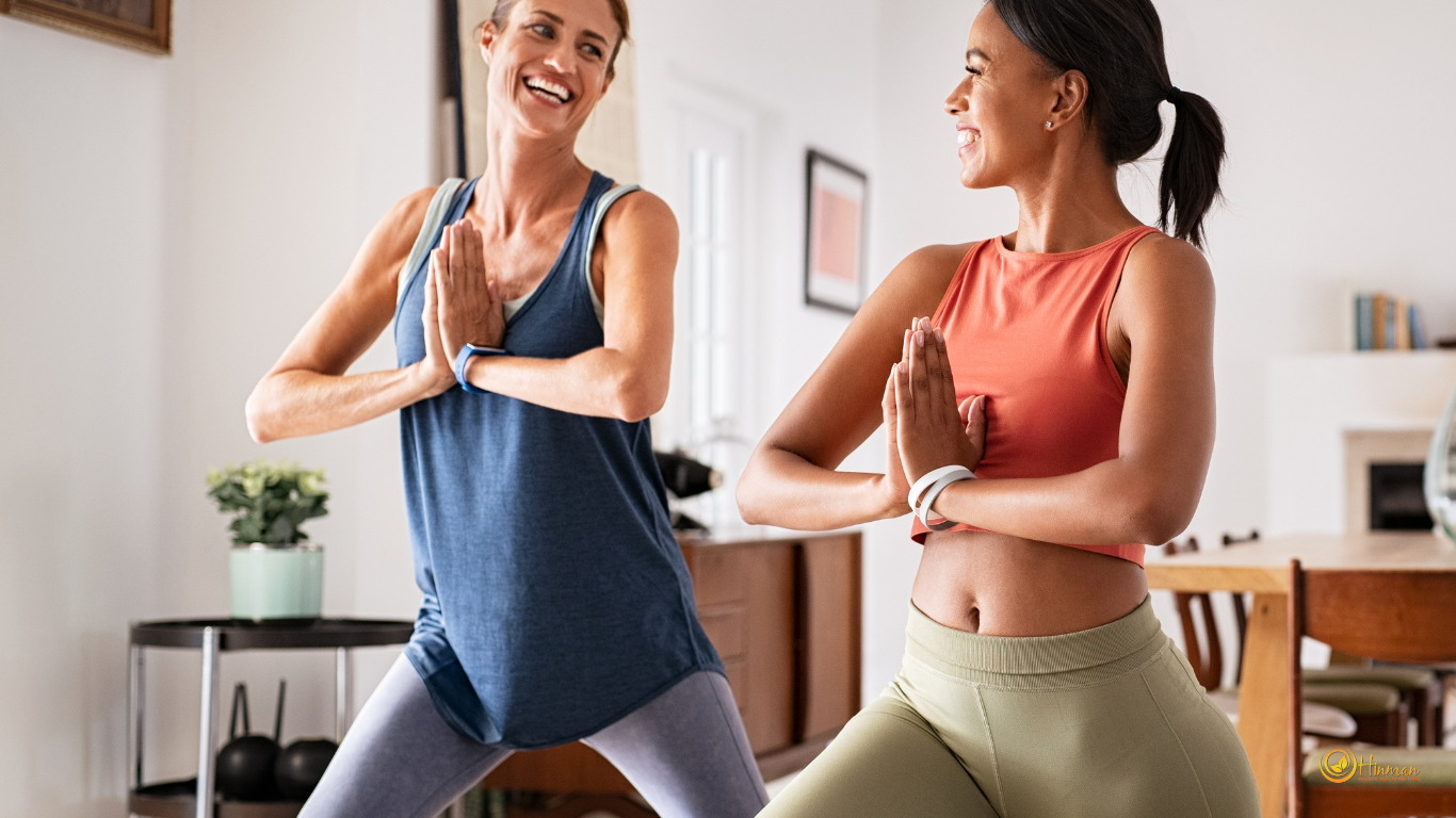 Two women smiling at each other while practicing yoga together