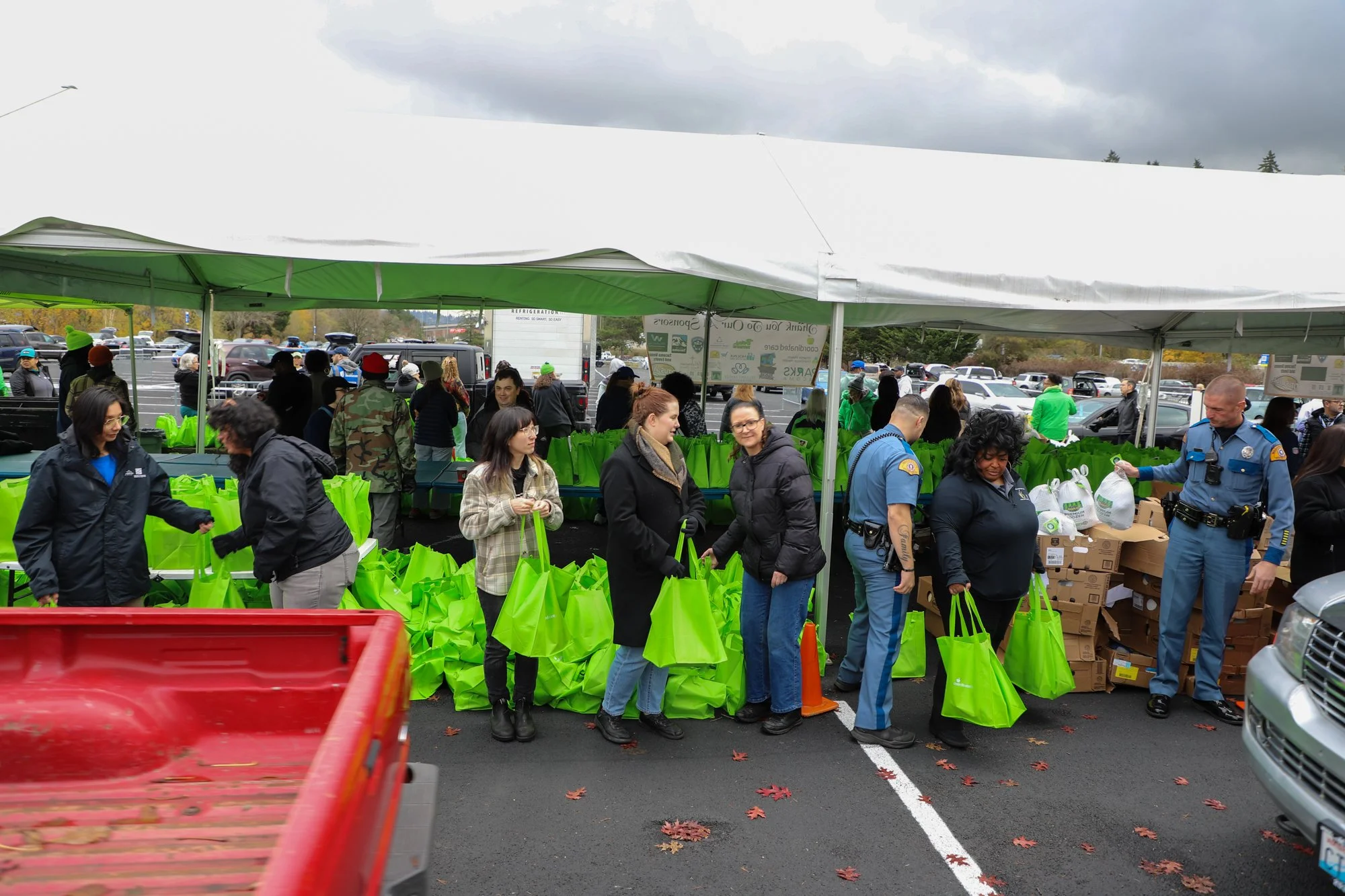 Photo of volunteers waiting for car holding bright green bags at the Tacoma Police Department Turkey Giveaway