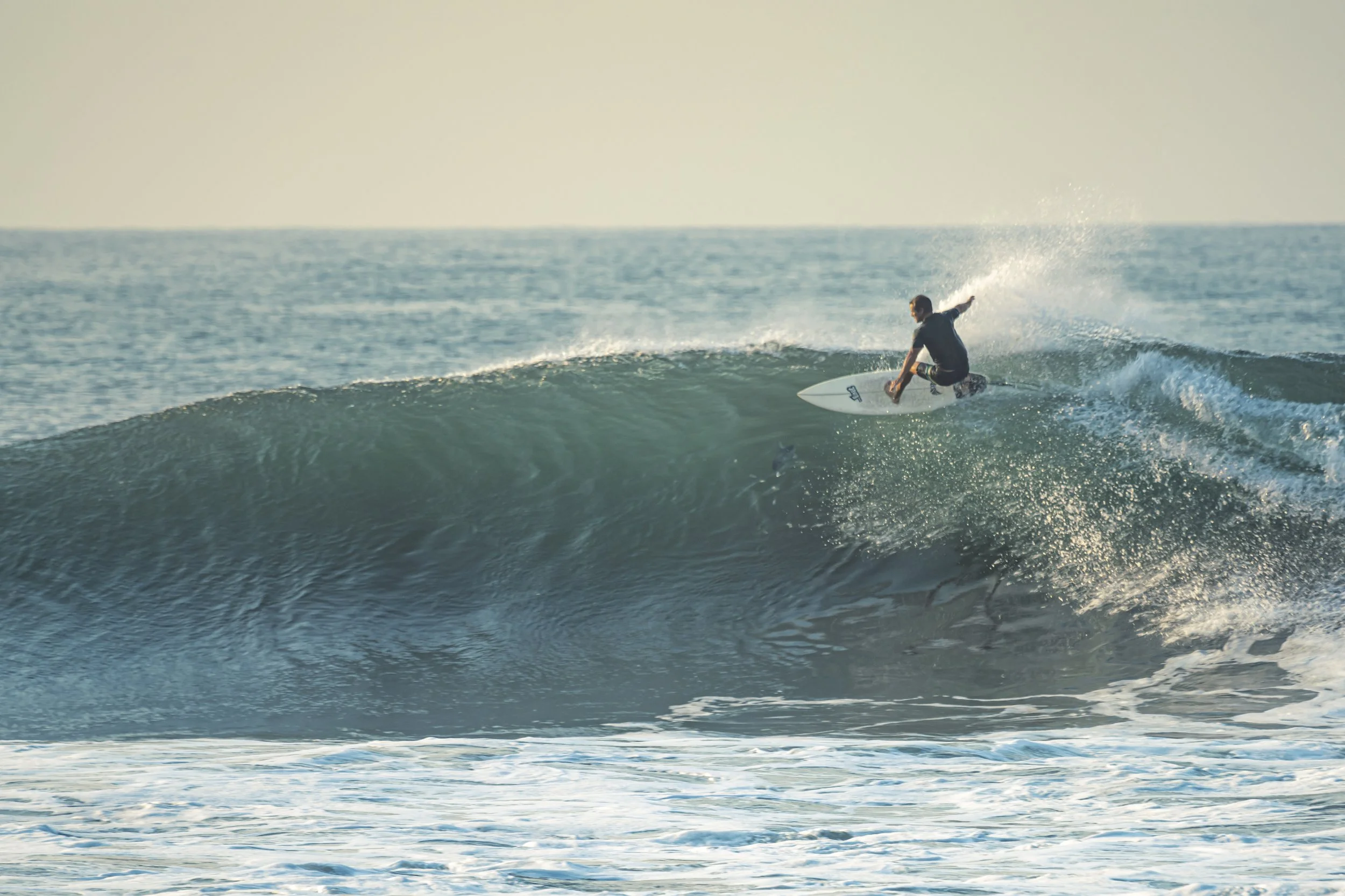 A person surfing on a wave in the ocean during daylight.