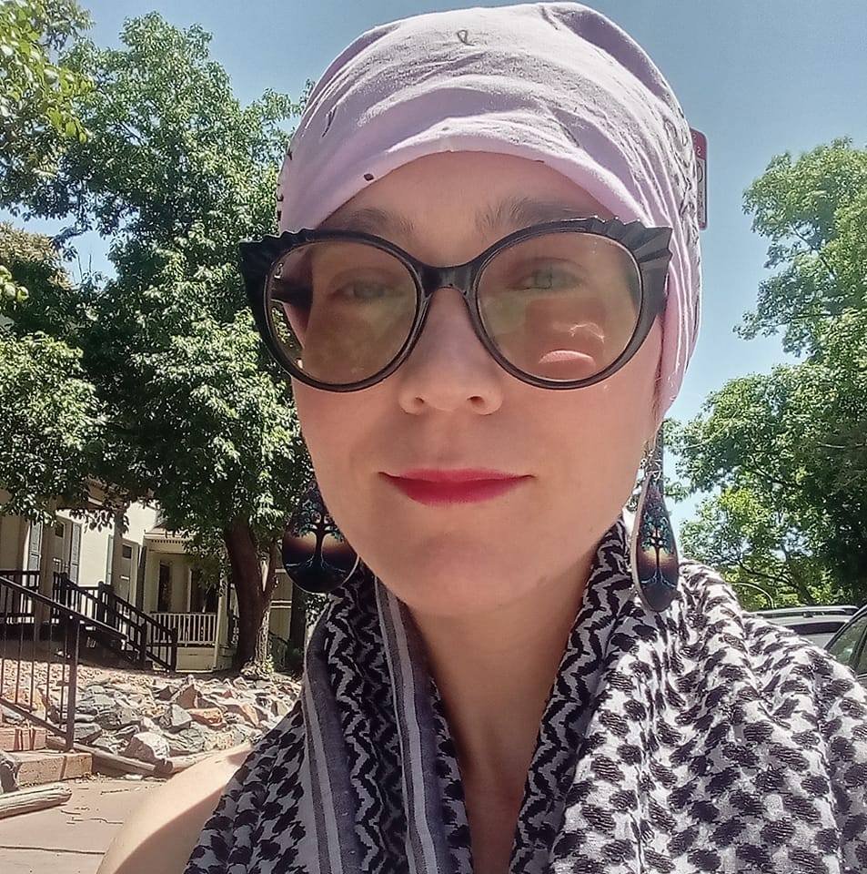 Woman wearing large sunglasses and a headscarf outdoors.