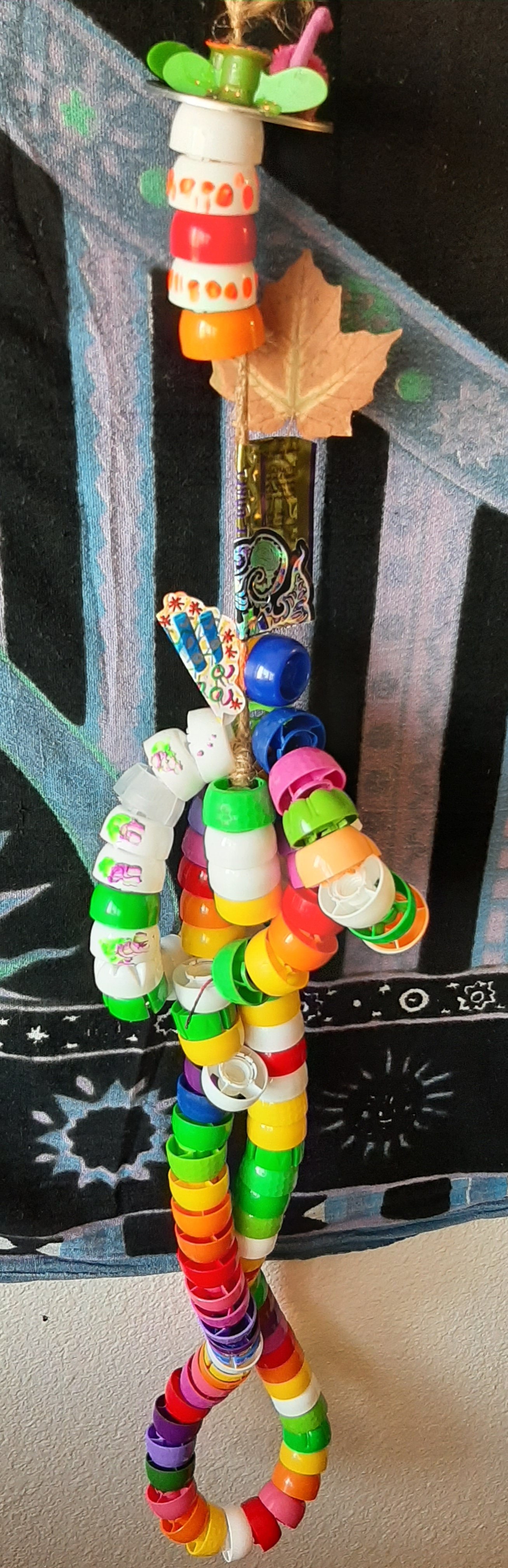 Colorful art piece made of stacked plastic caps and decorative elements.