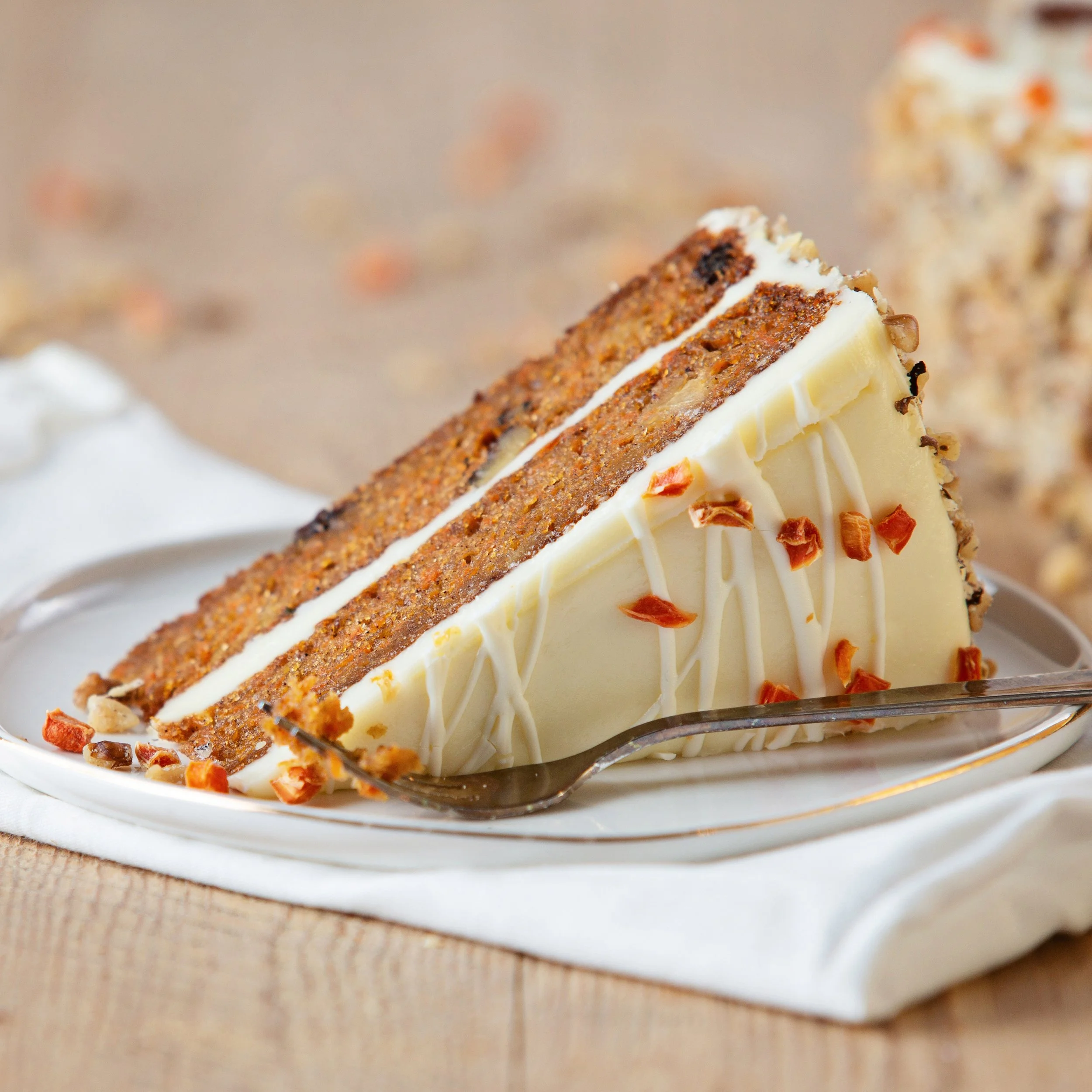 From an old family recipe—dark, fruity and moist wrapped in a cream cheese frosting, flecked with bright orange
carrots and ribboned with a contrasting white chocolate drizzle.