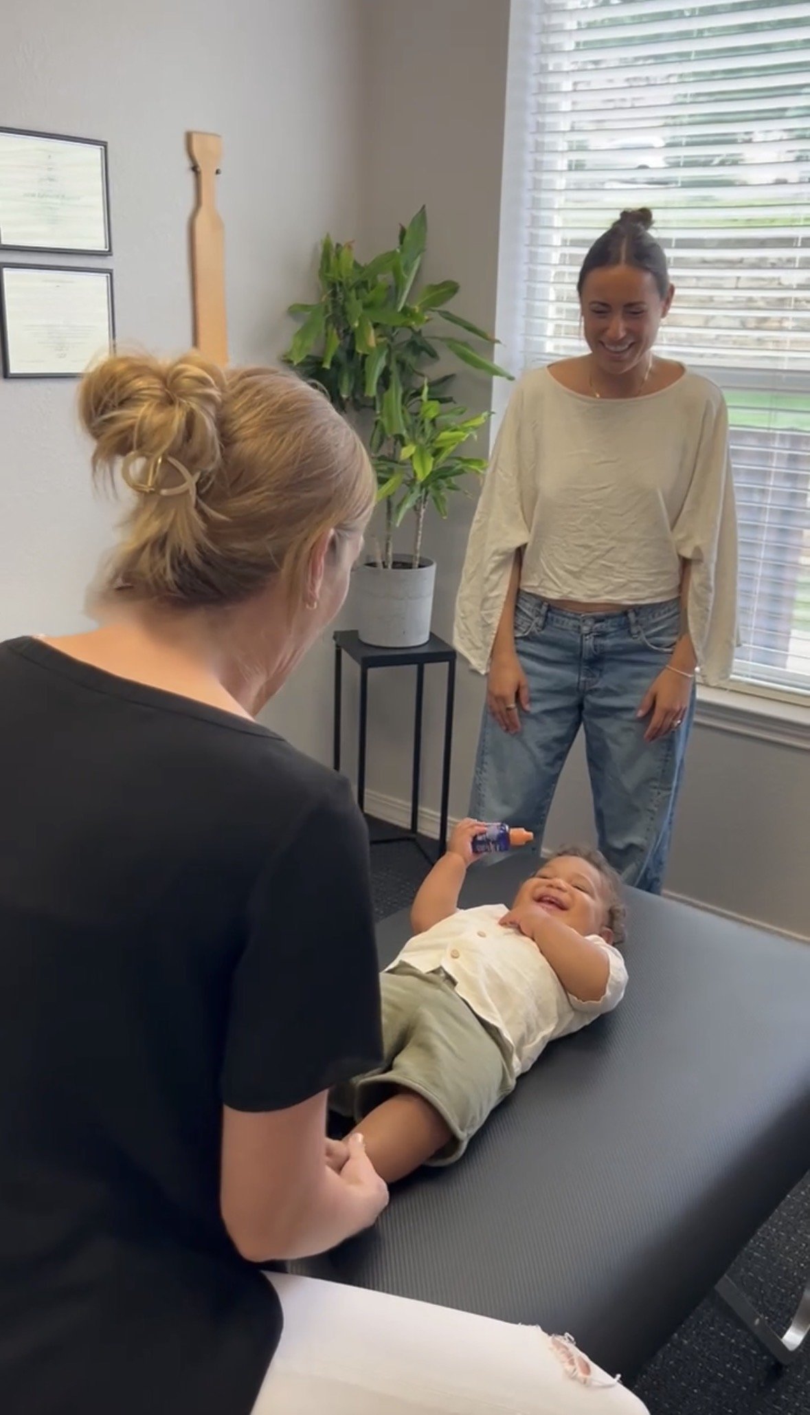 Dr. Alicia Bagwell providing gentle pediatric chiropractic care to a baby while mom looks on, at Be Well Chiropractic in Lakeway, TX