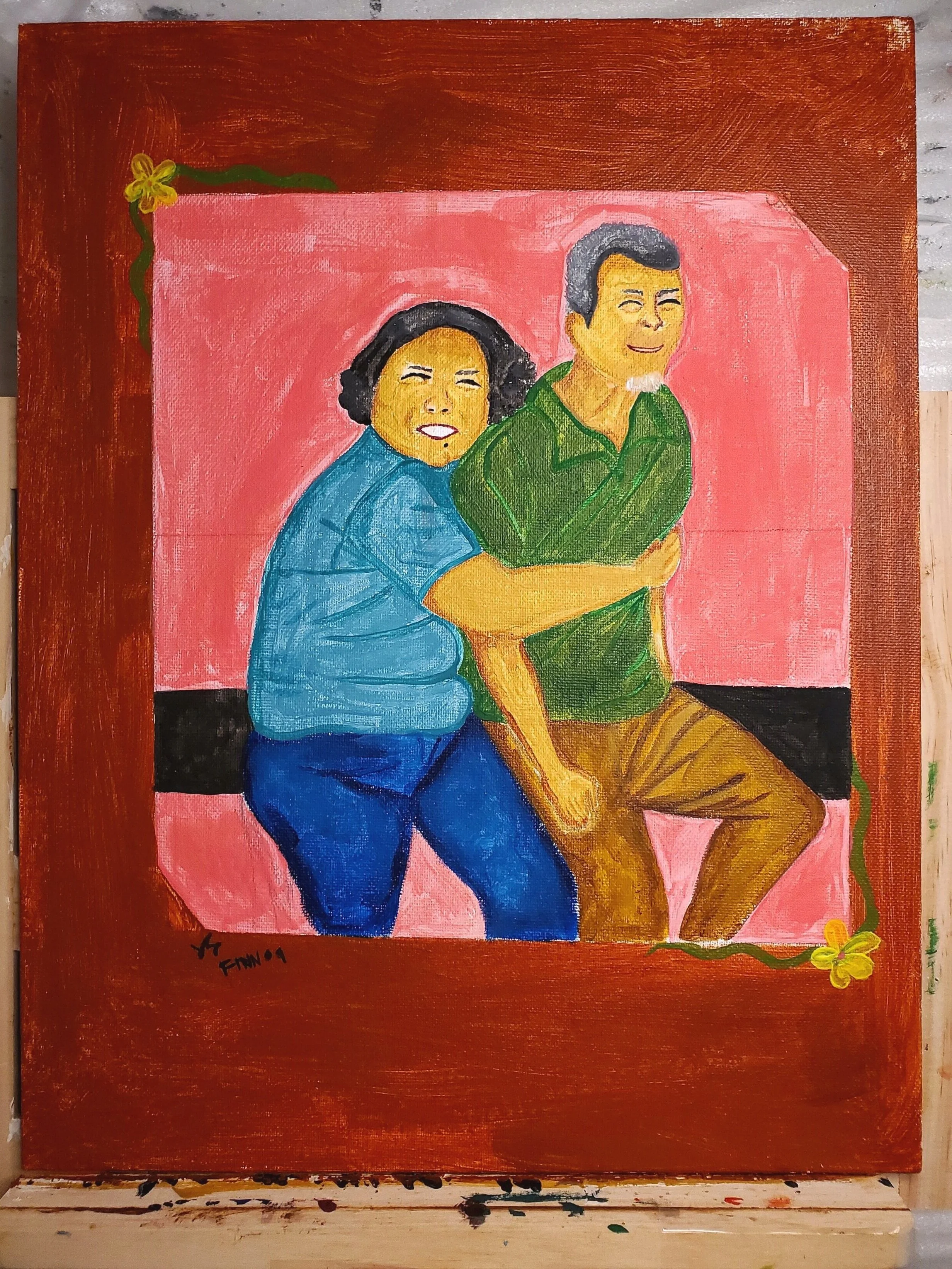 Painting of two people, a woman and a man, smiling and hugging while sitting on a pink background with a brown border decorated with yellow flowers and green vines.