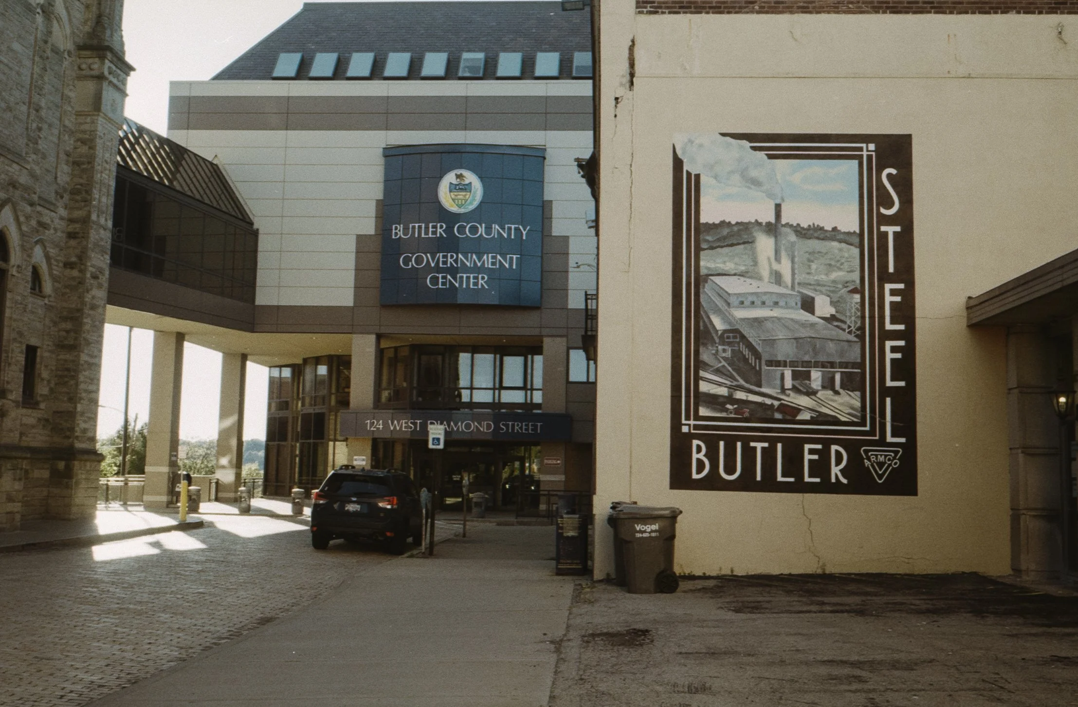 Entrance to Butler County Government Center with a sign displaying the address 124 West Diamond Street, and a large mural of a factory or plant with the word 'STEEL' on it.