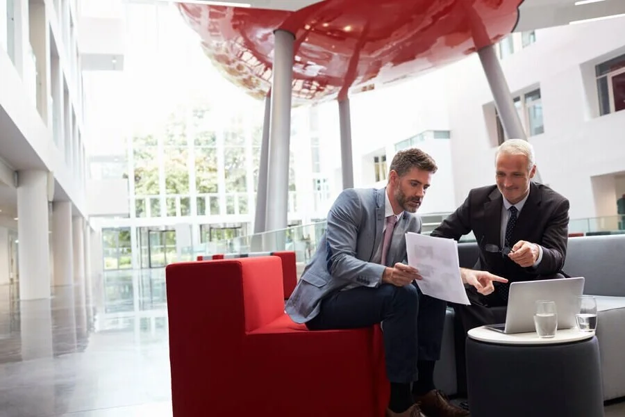 two-businessmen-discuss-document-in-lobby-of-moder-PECYPAQ.jpg