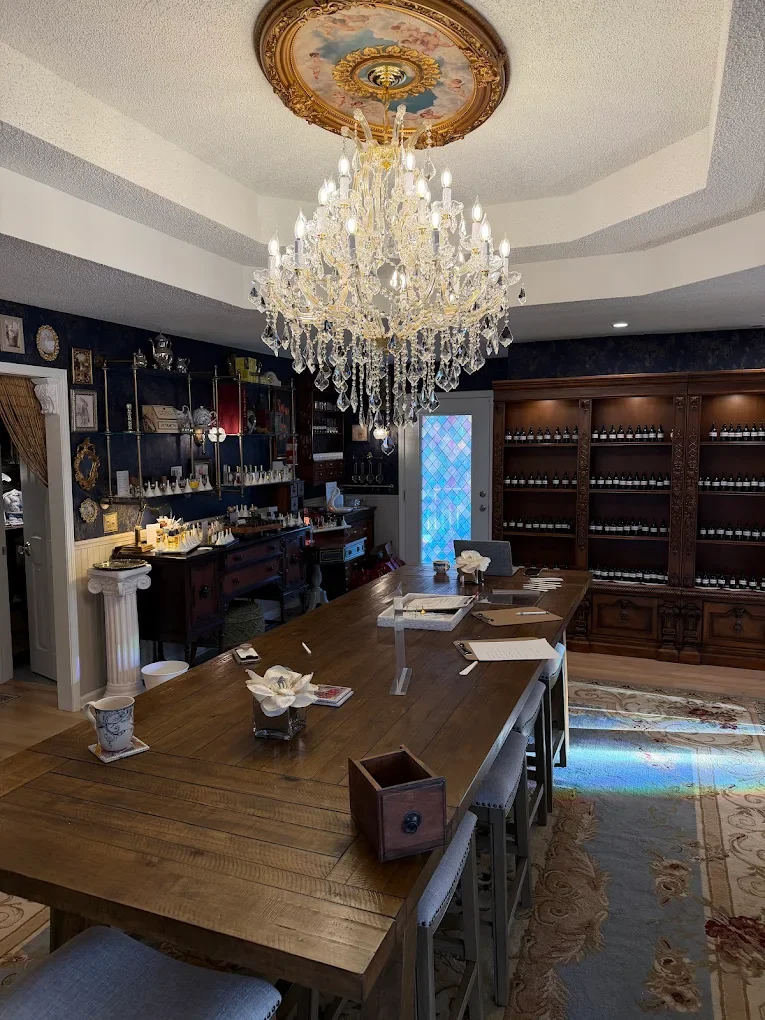 A luxurious dining room with a large wooden table, a crystal chandelier, dark wood bookshelves, and a decorative ceiling medallion.