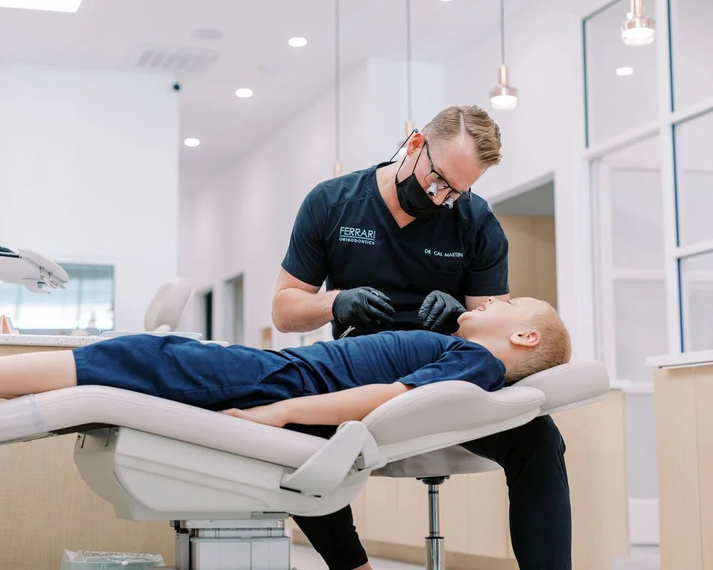 An orthodontist examining a young boy lying on a dental chair in a modern dental clinic.