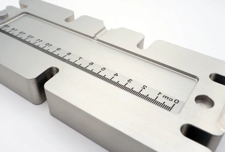 Close-up of an open aluminium injection mould showing the cavity face and the two halves that clamp together.