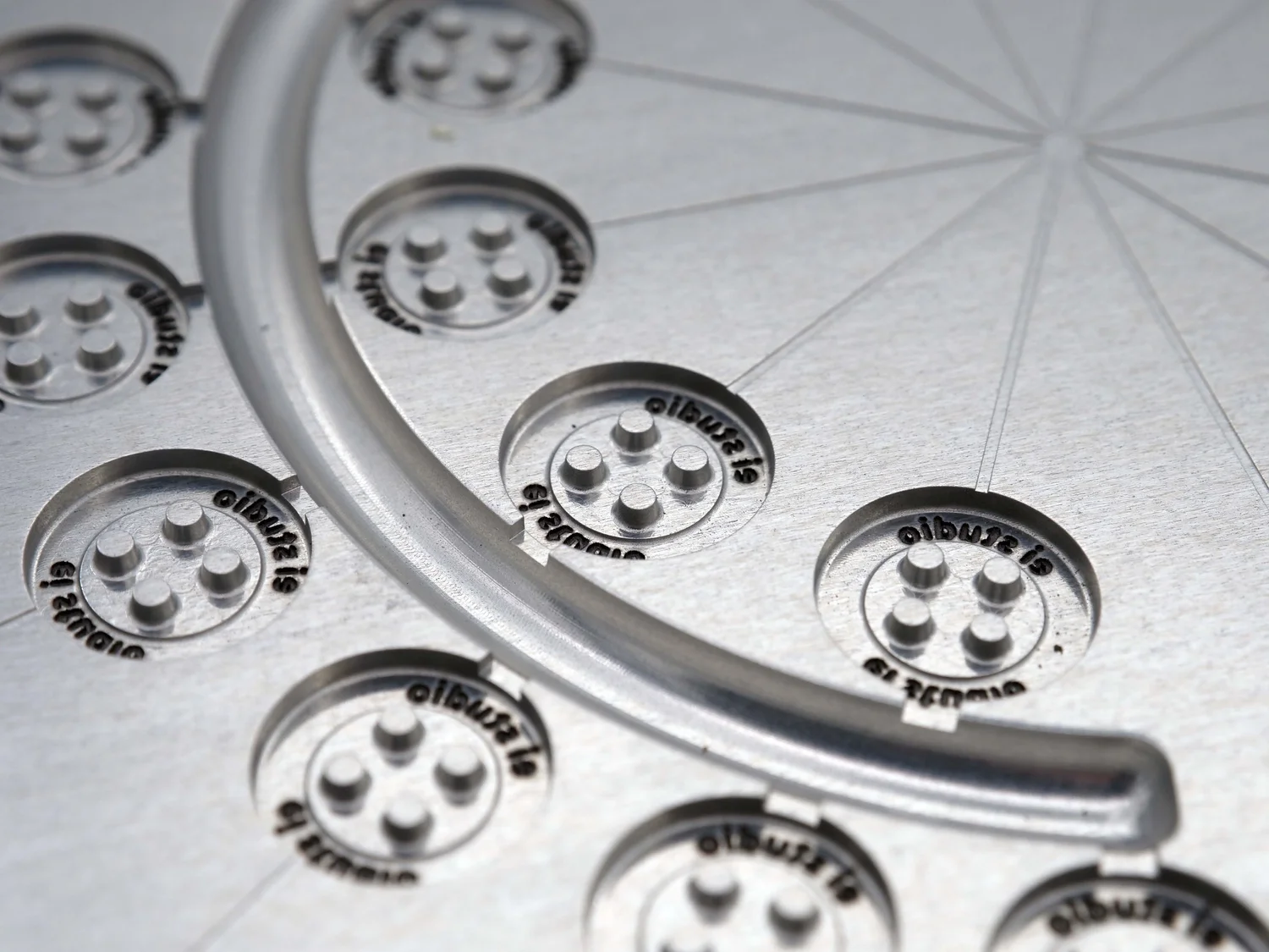 Small button moulded in recycled plastic with custom logo engraving on the cavity face