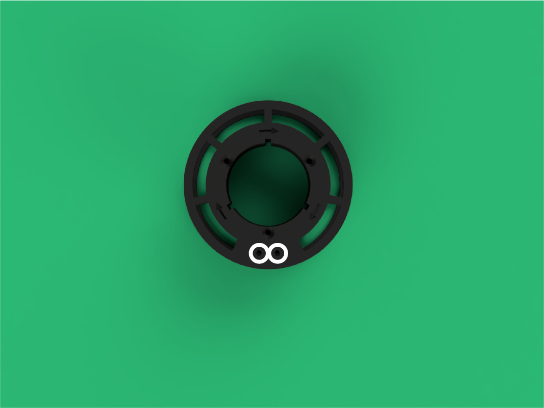 A black circular mount or adapter on a green surface with two small white circles near the bottom.