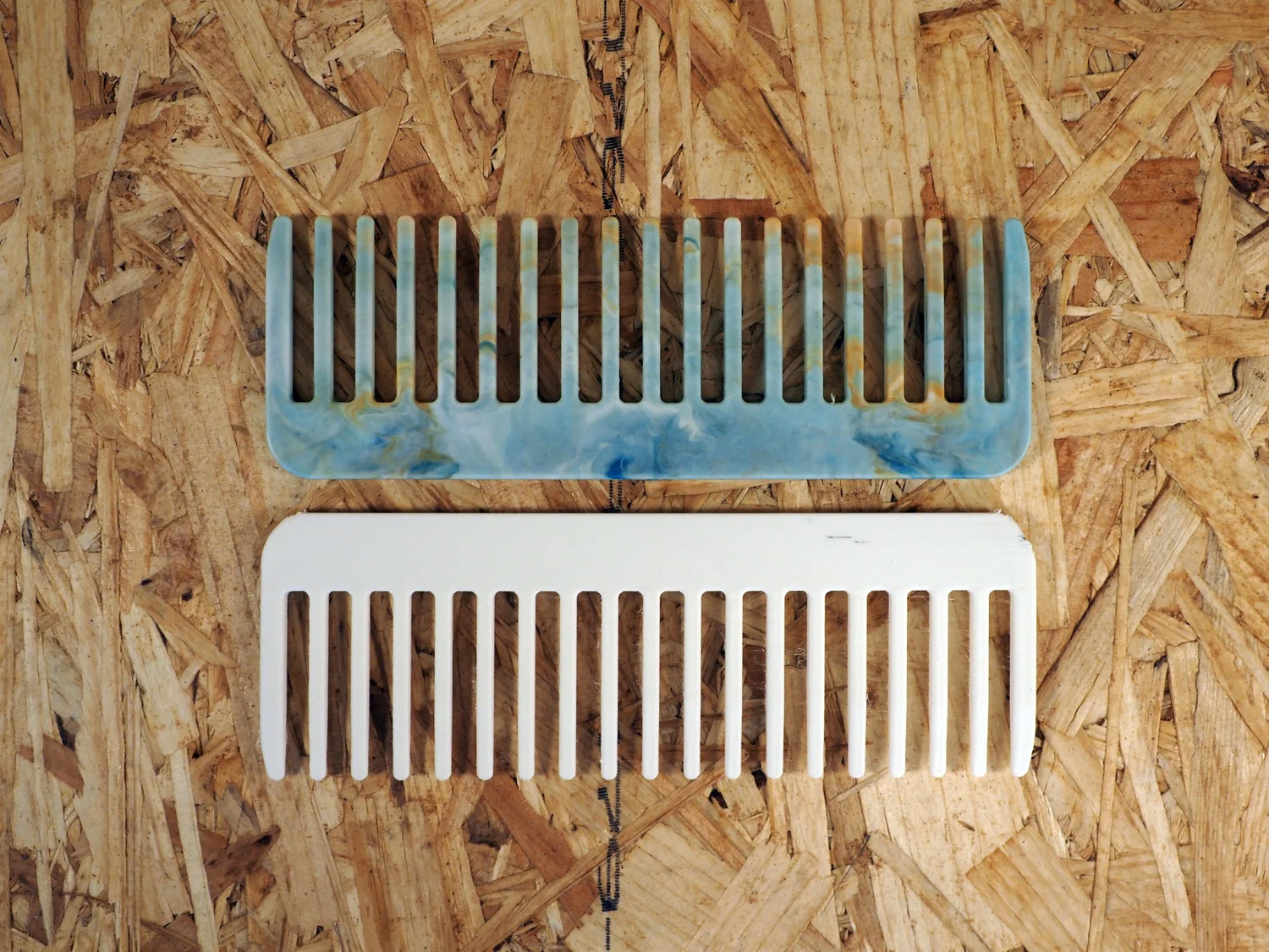 The comb test, 42 injection-molded recycled-plastic combs lined up next to a single 3D-printed comb from the same time window.