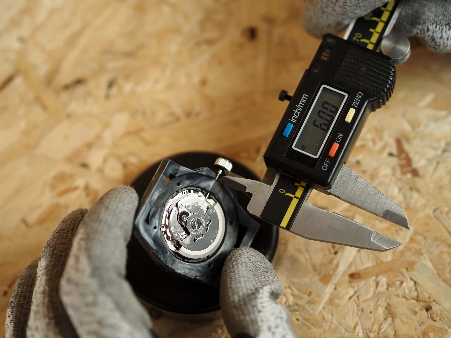 Callipers measuring the crown-to-case gap before trimming the stem.