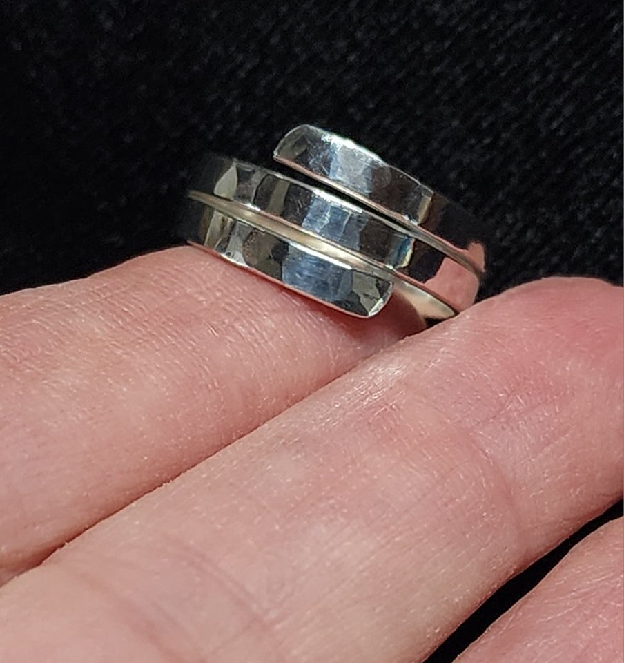 New--hammered Argentium silver triple-wrap ring. The shank is soldered along the bottom, and the top has a bypass design with lots of texture and high polish. I originally thought I'd be adding one or more bezel-set stones, but it stands well on its 