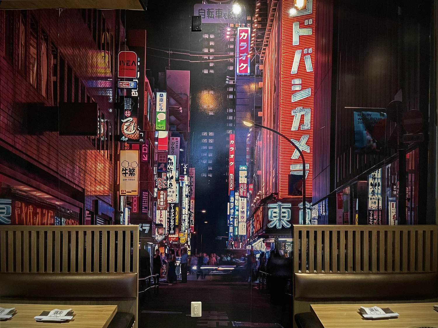 Gyu Shige's dining booths beneath a neon Tokyo street mural